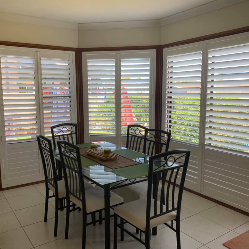 A Dining Room With A Table And Chairs And Shutters On The Windows — Outdoor Blinds In Berkeley Vale, NSW
