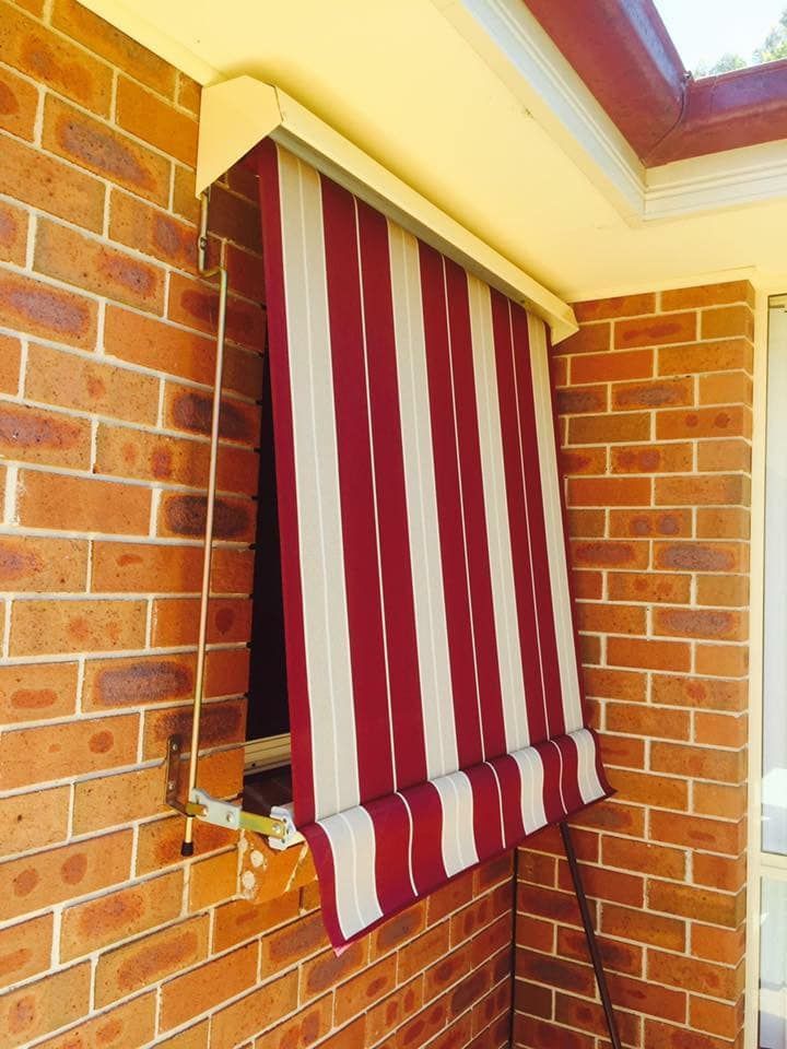 A Window With A Red And White Striped Awning On It — Outdoor Blinds In Lake Macquarie, NSW