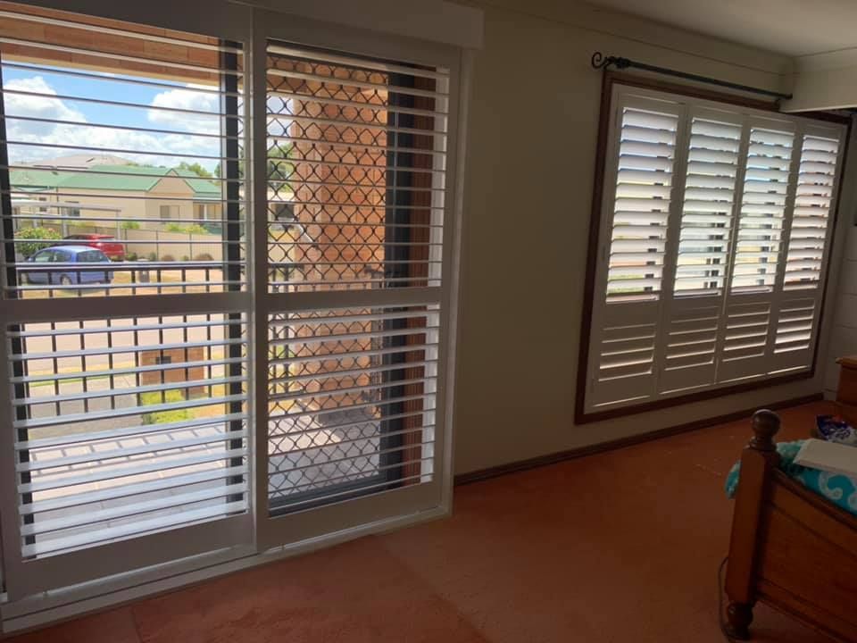 A Bedroom With Sliding Glass Doors And Shutters On The Windows — Outdoor Blinds In Lake Macquarie, NSW