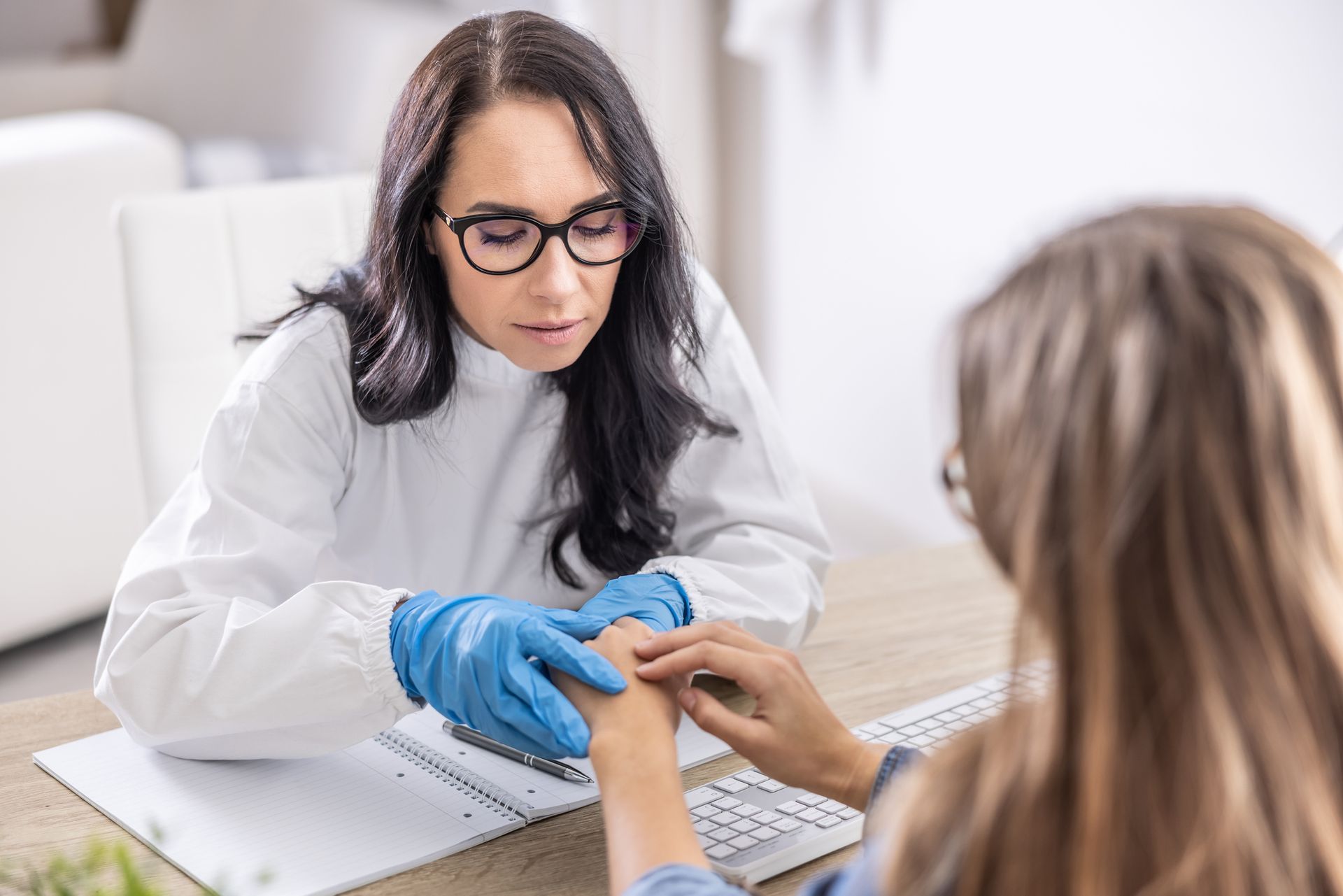 Healthcare worker in gloves holding patient's hand during consultation