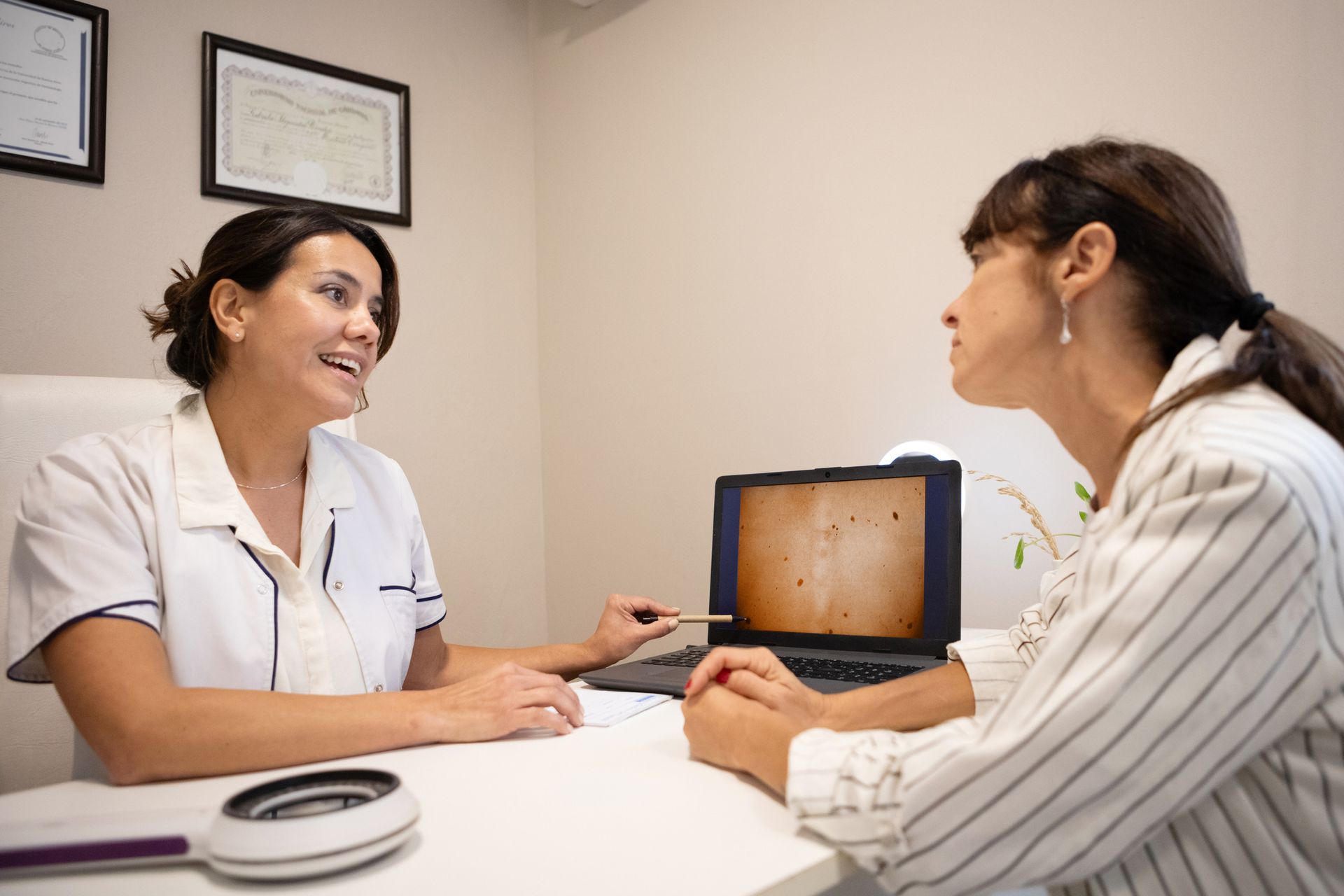 Dermatologist discussing melanoma treatment options with a female patient. Dermatologist discussing melanoma treatment options with a female patient.