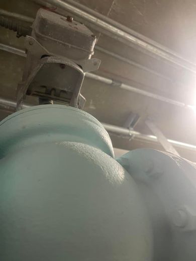 Large, light blue water tank with a metal control box attached to it, viewed from below.