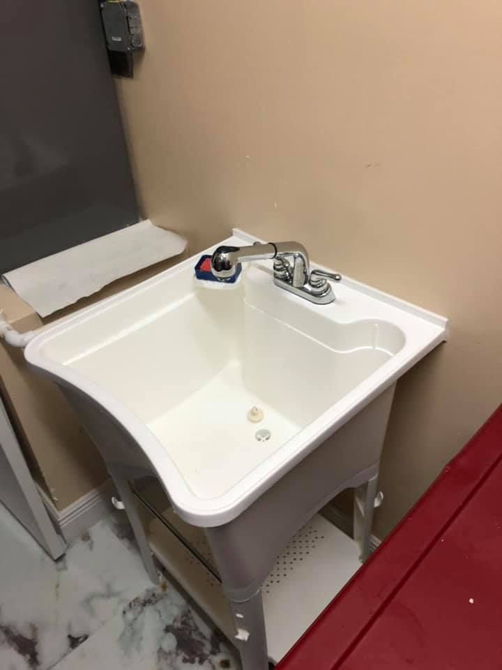 White utility sink with chrome faucet, in front of a beige wall in a utility room.