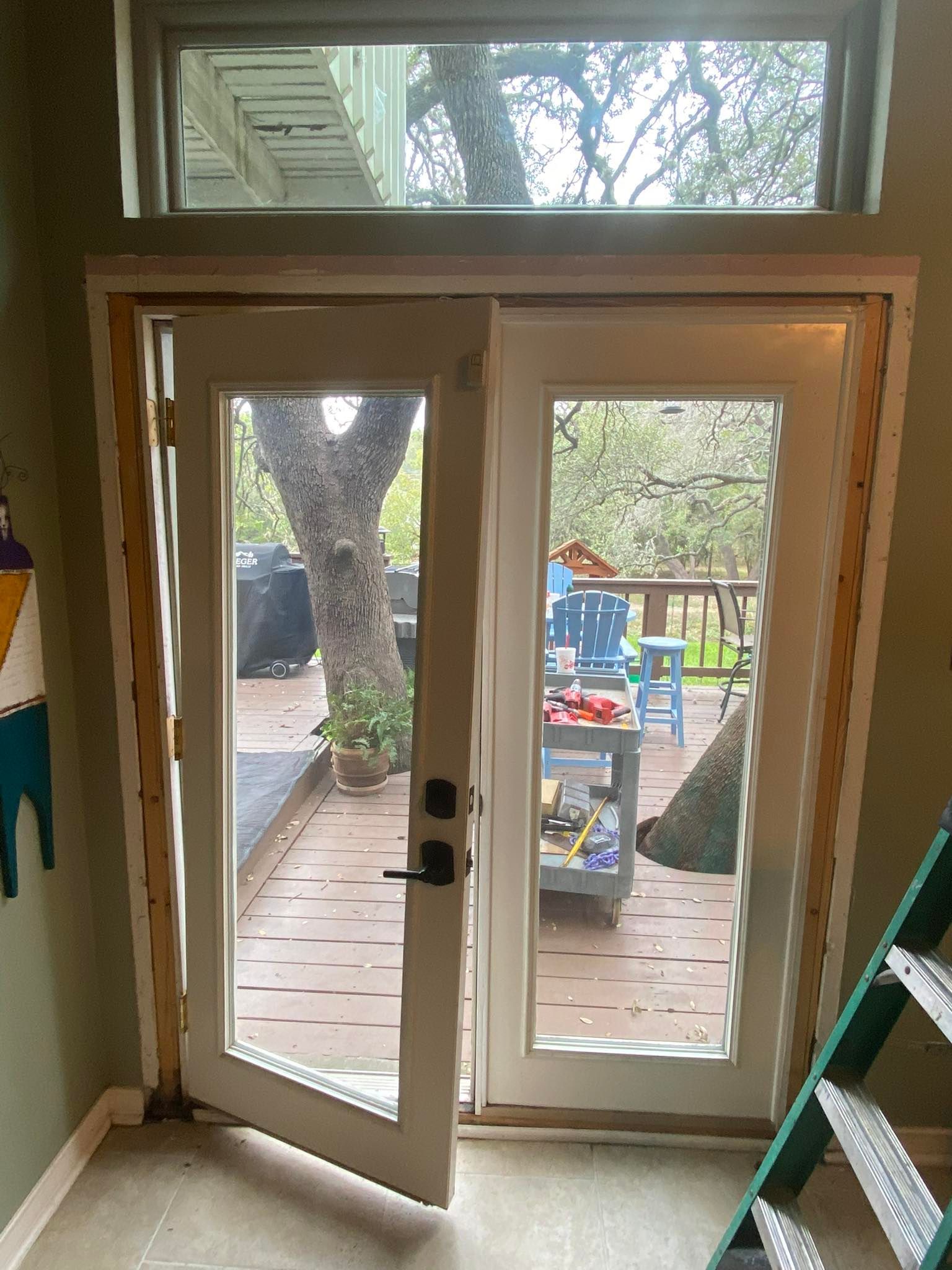 Two glass doors opening to a deck, framed by unfinished wood trim. A small window is above.