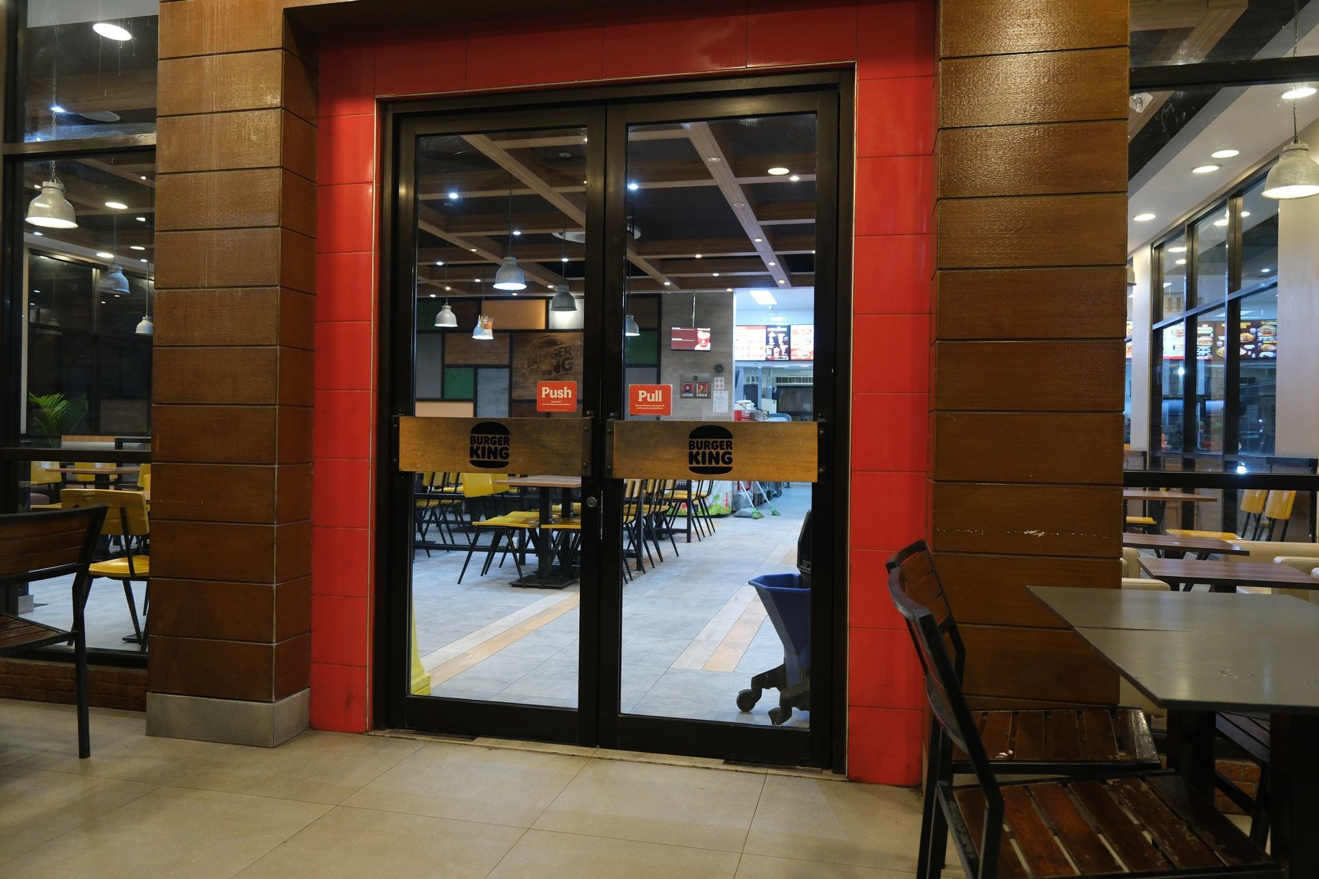 Double glass doors framed in red, leading into a restaurant with tables and chairs.