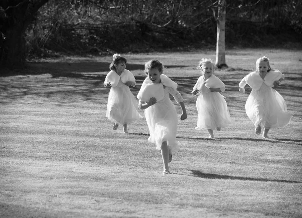 Bridesmaids running across the lawn at New Barn Farm, Calbourne, Isle of Wight