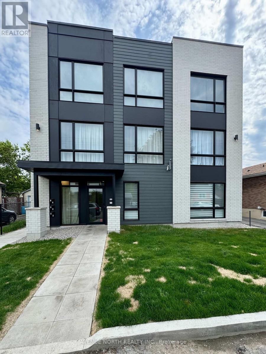 Un grand immeuble d'appartements avec beaucoup de fenêtres et une pelouse verte luxuriante devant lui.