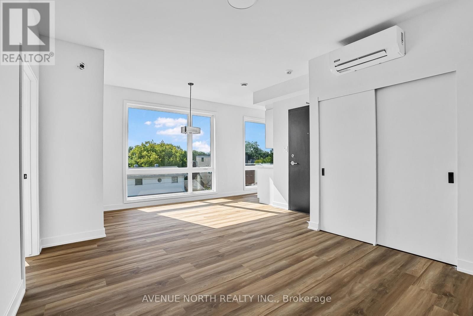 Une grande pièce vide avec du parquet et des murs blancs.