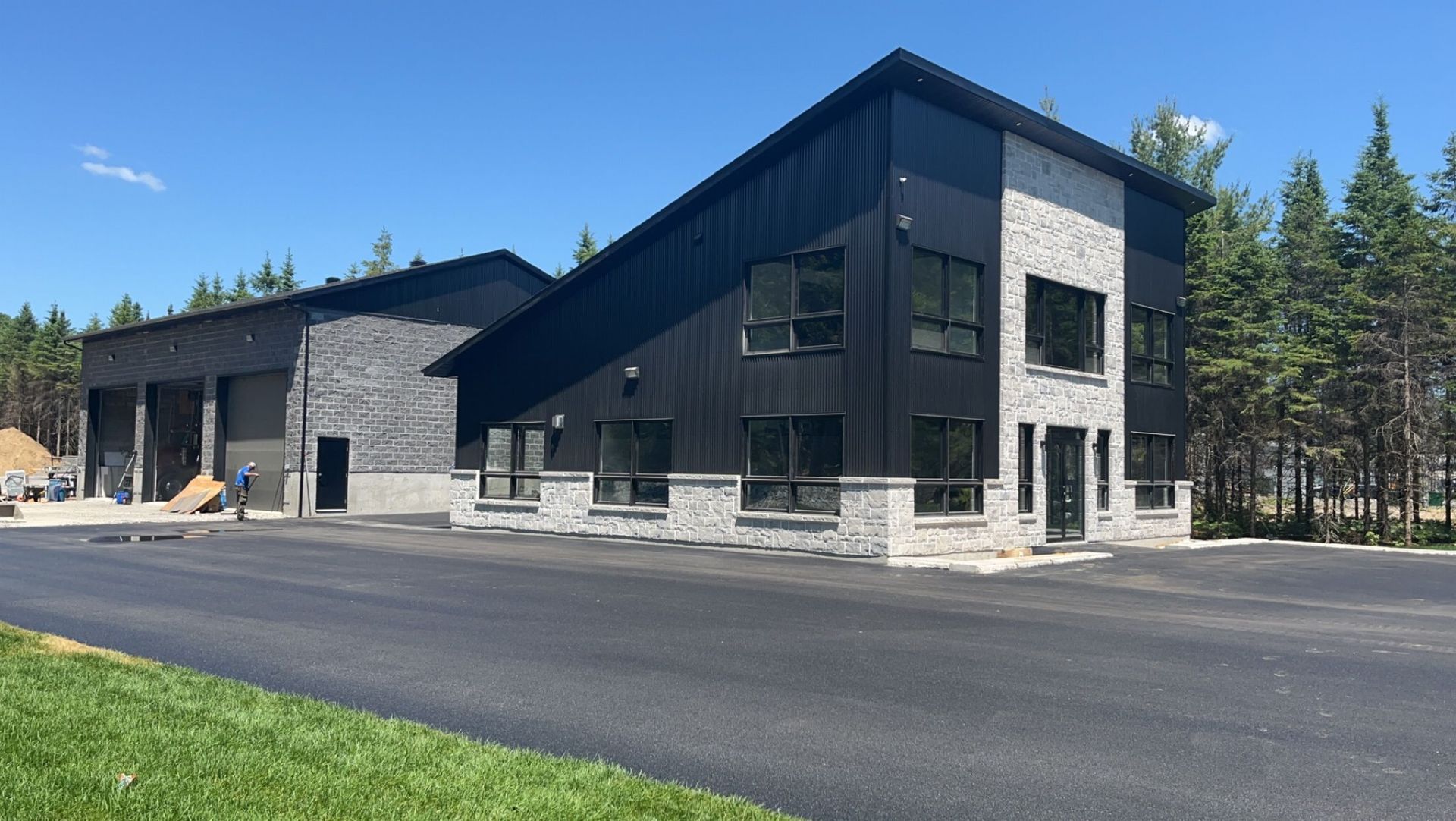 Un grand bâtiment noir avec beaucoup de fenêtres se trouve à côté d'une route.