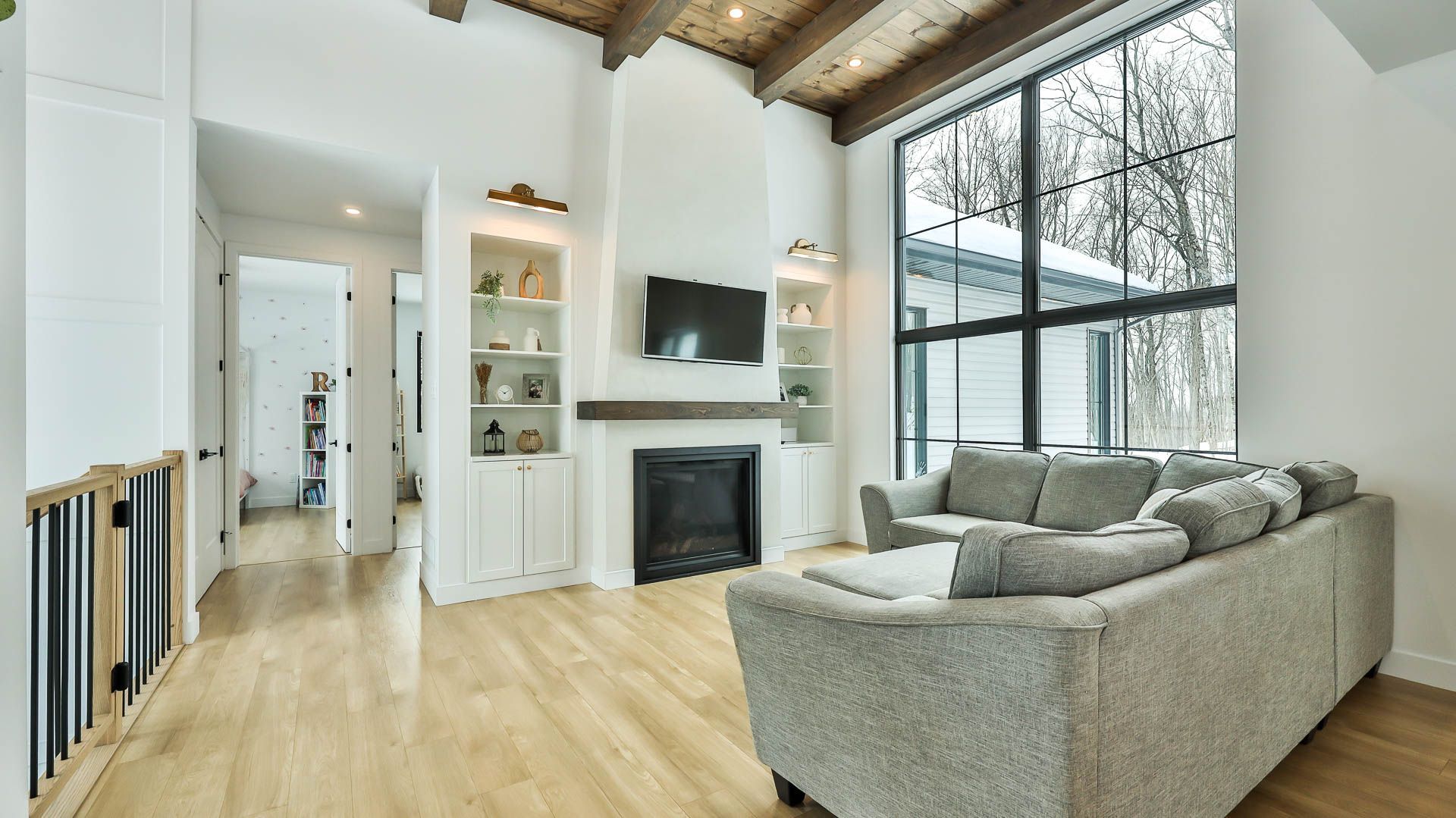 Un salon avec un canapé, une cheminée, une télévision et de grandes fenêtres.