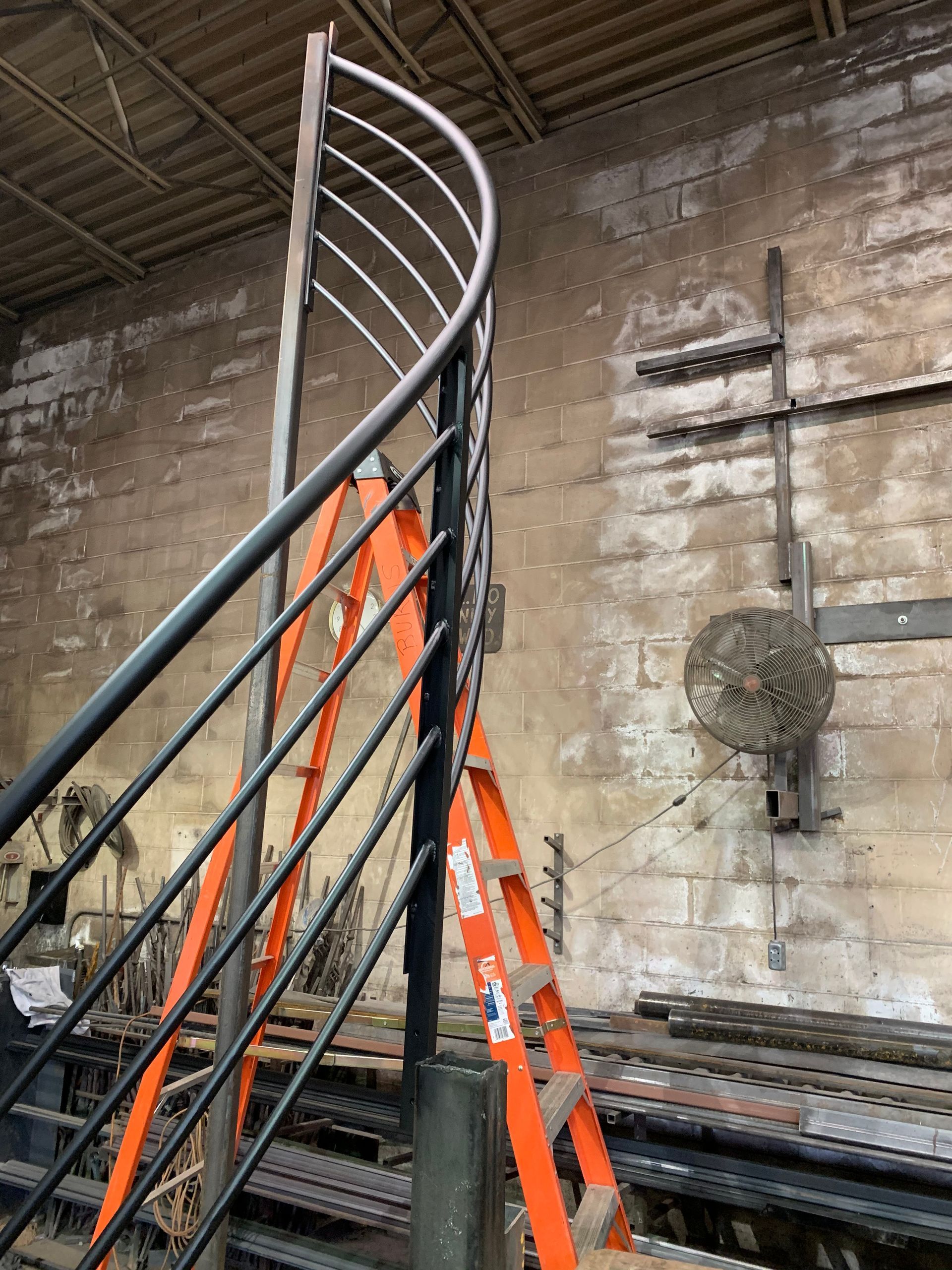 A spiral staircase with a ladder attached to it in a warehouse.