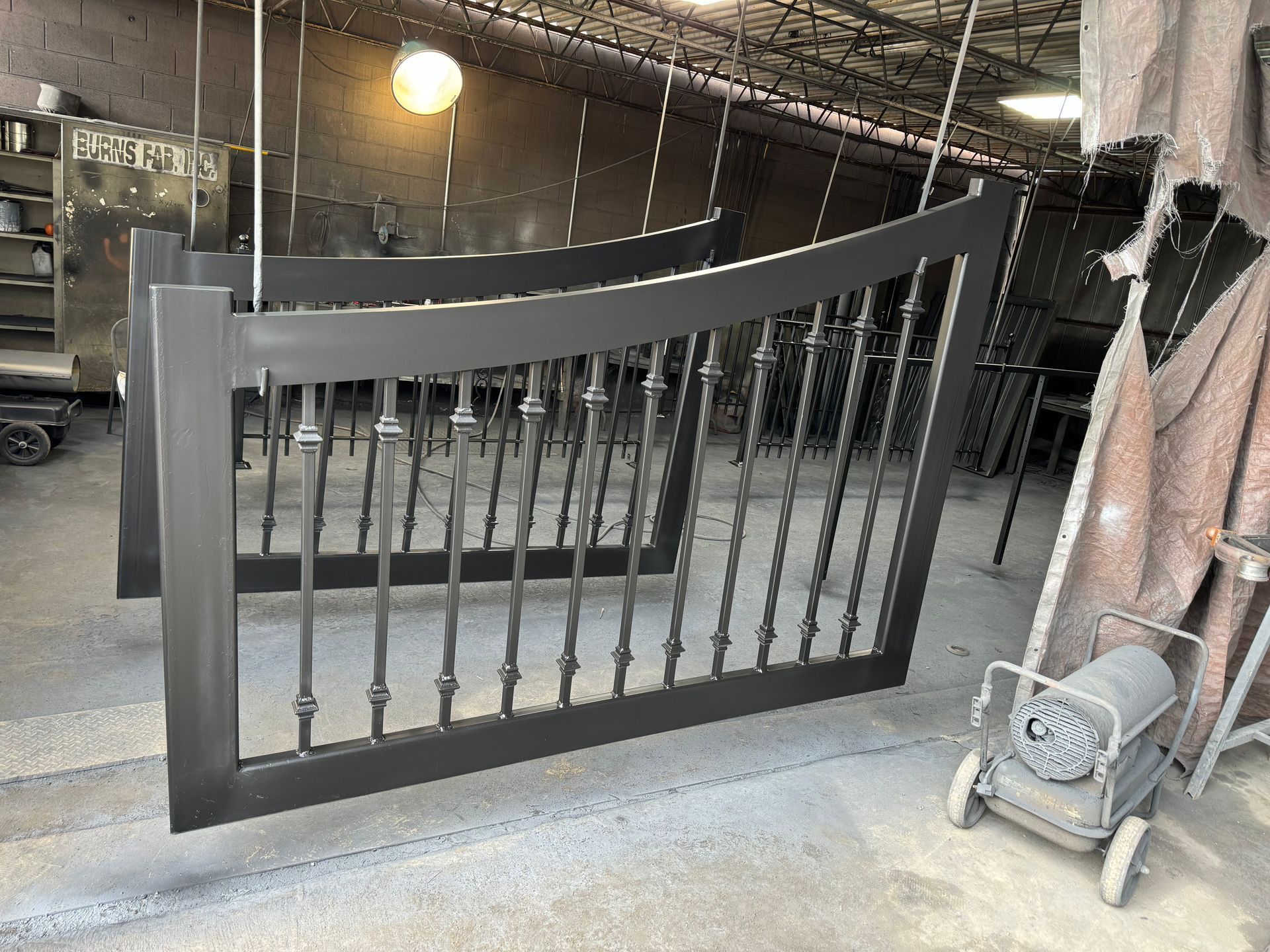 A black metal fence is being painted in a factory.