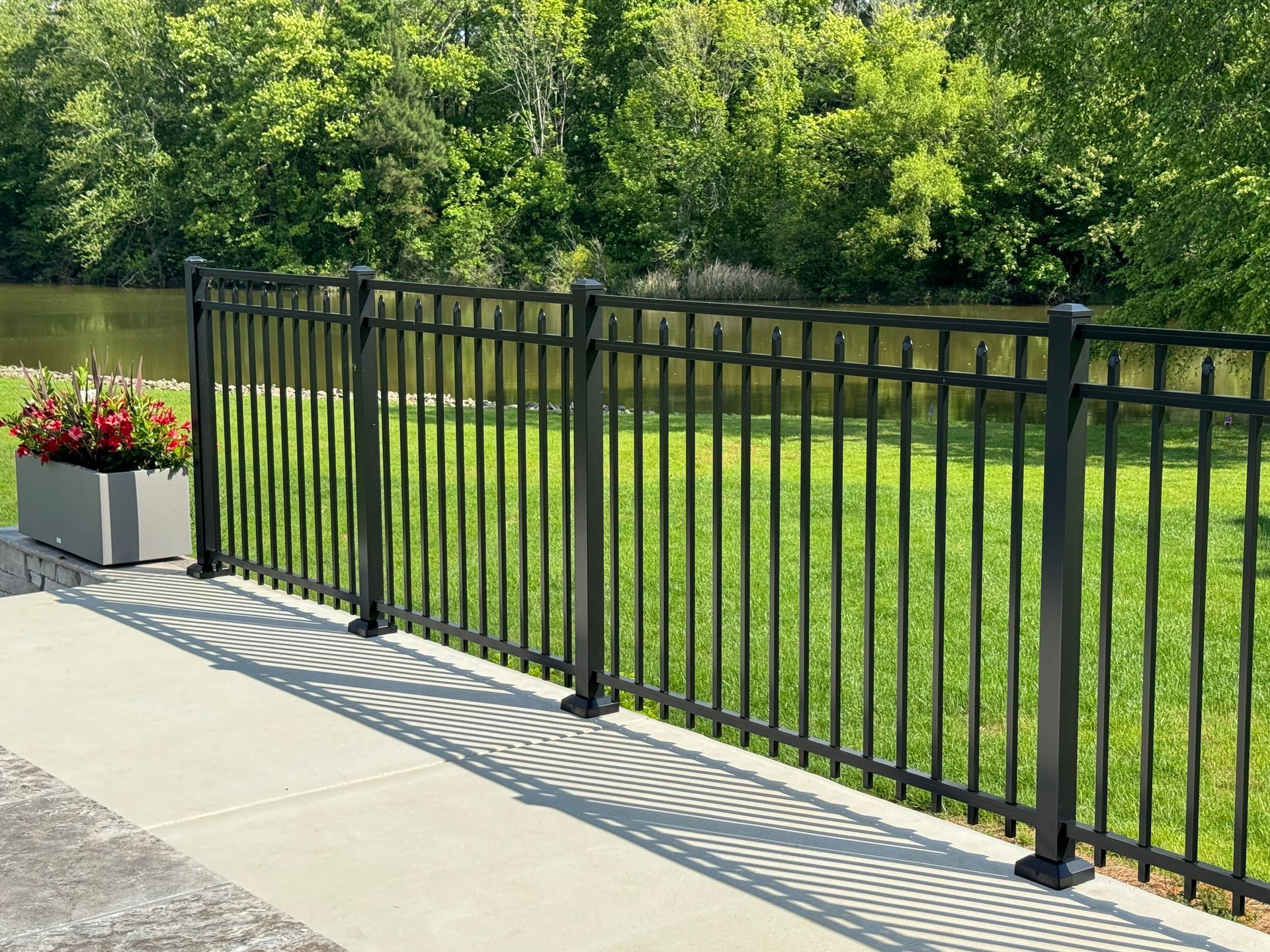 A black metal fence surrounds a lush green field.