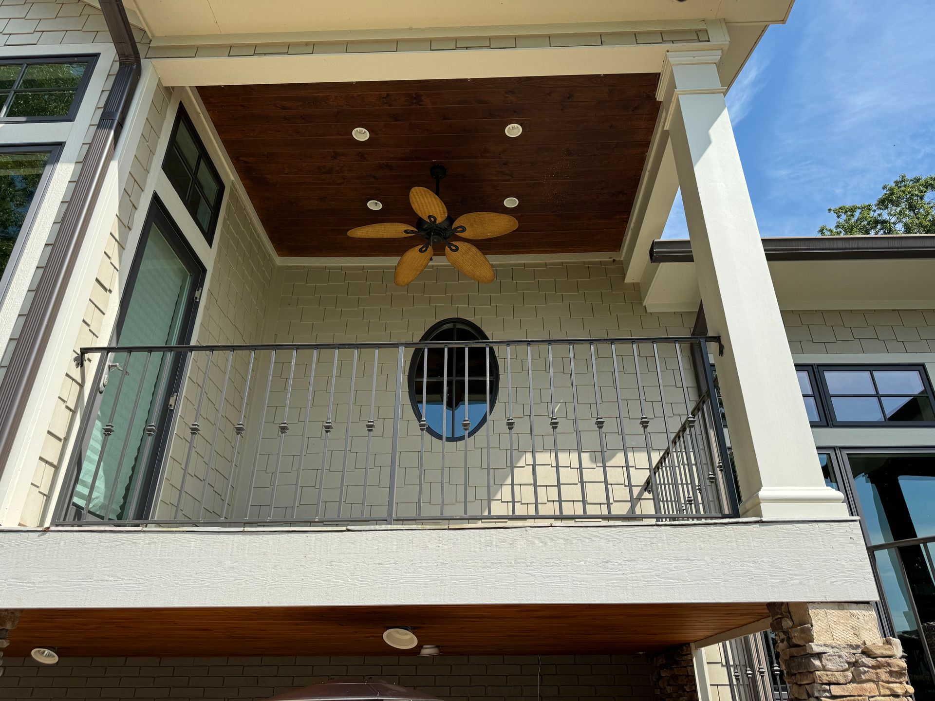 A balcony on the side of a house with a ceiling fan.