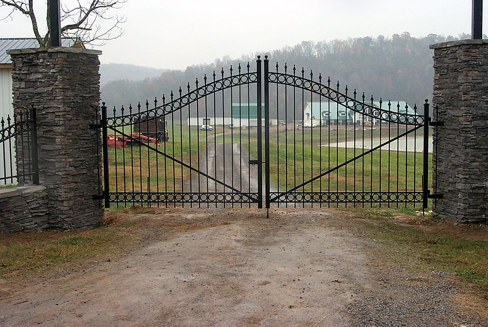 A wrought iron gate is open to a dirt road