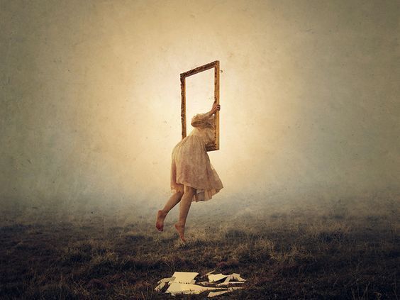 A woman is hanging upside down in the air holding a picture frame.