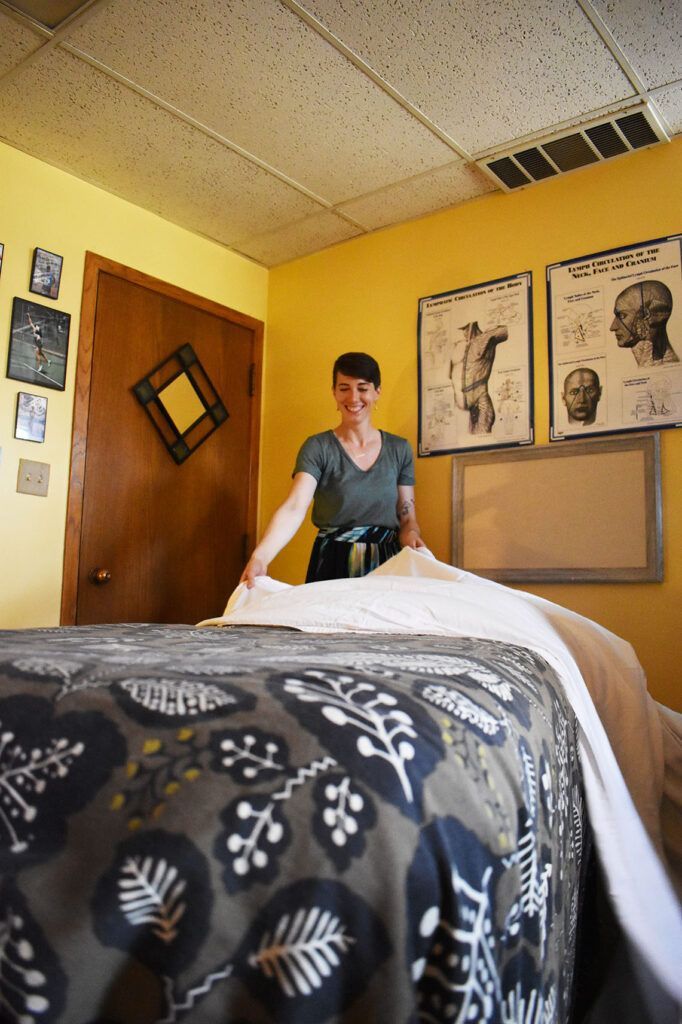A woman is standing next to a bed in a room