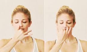 A woman is doing a yoga pose with her hands on her nose.