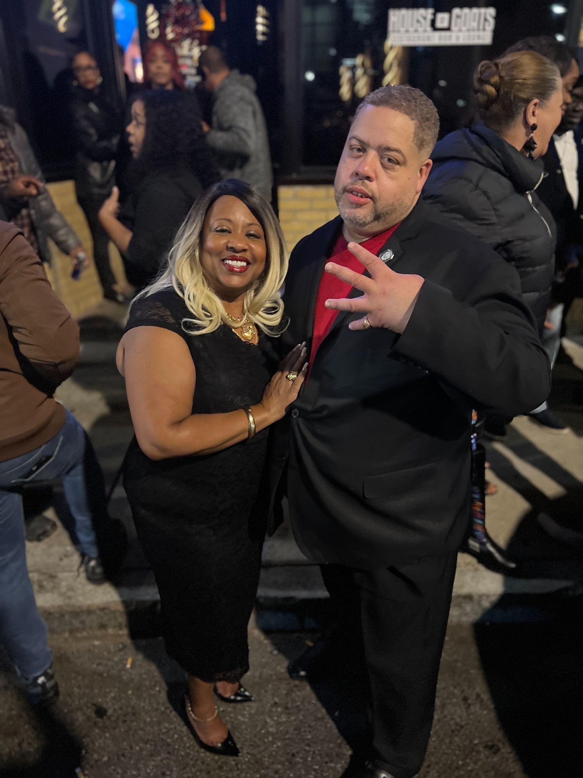 A man and a woman are posing for a picture in front of a crowd.