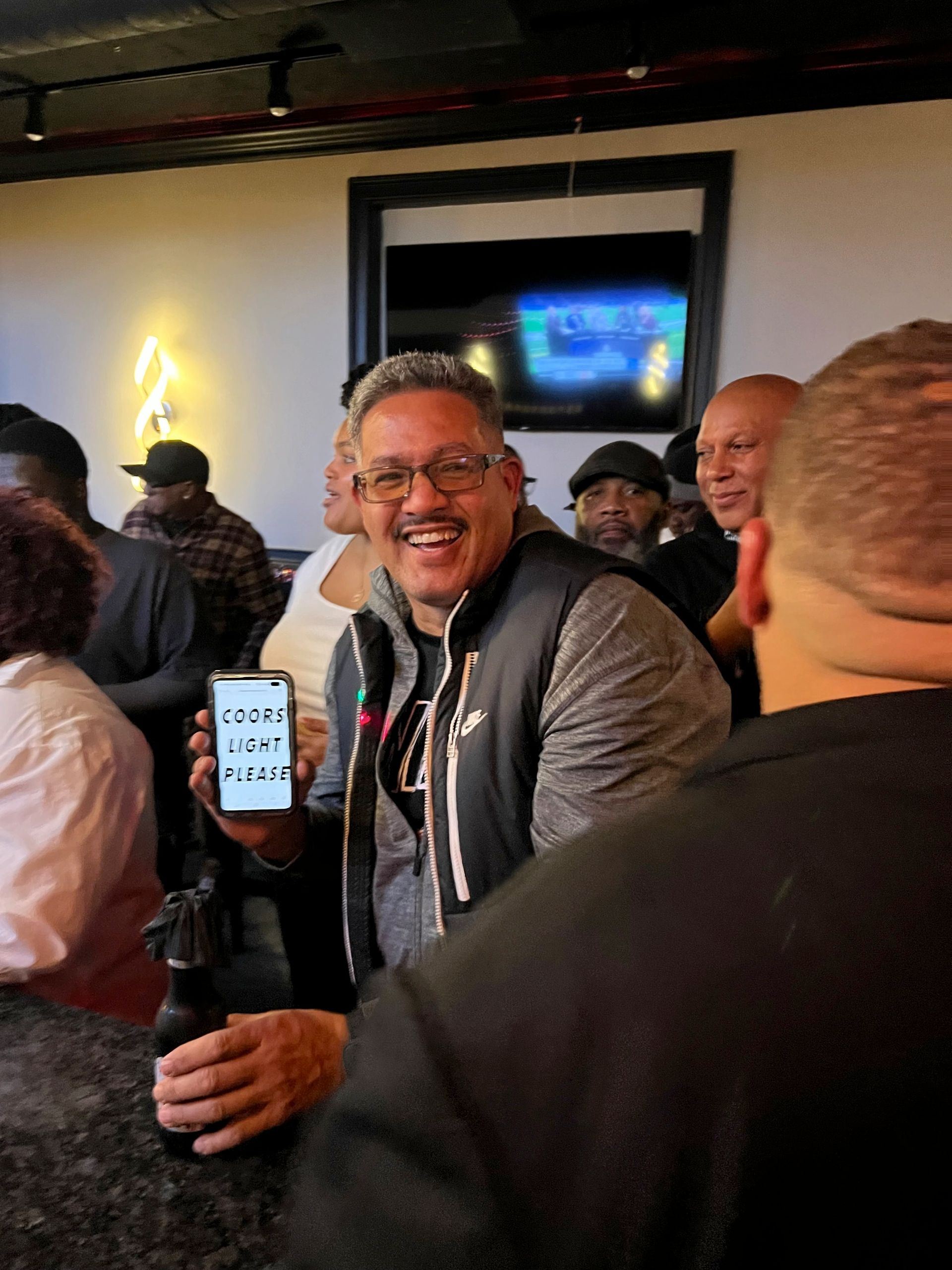 A man is holding a cell phone that says coors light on it