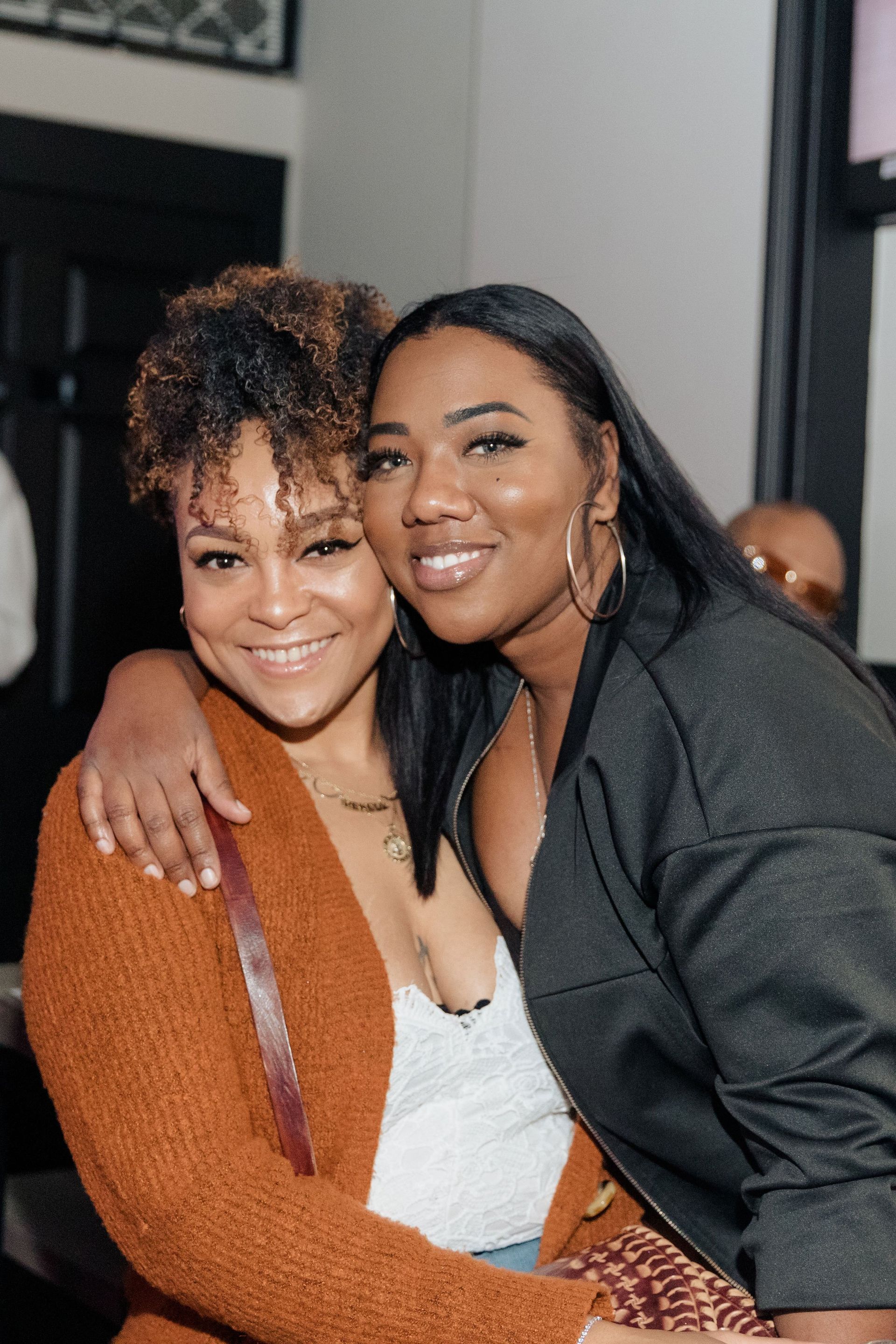 Two women are posing for a picture together and smiling for the camera.