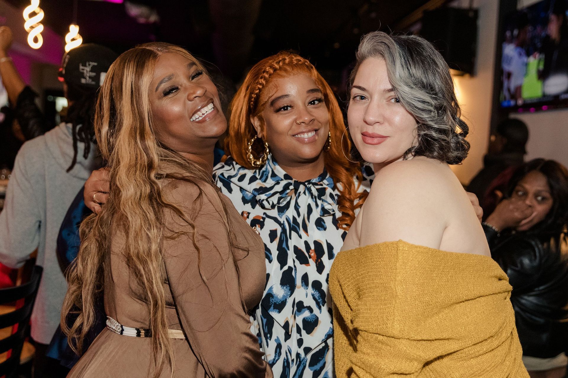 Three women are posing for a picture together at a party.