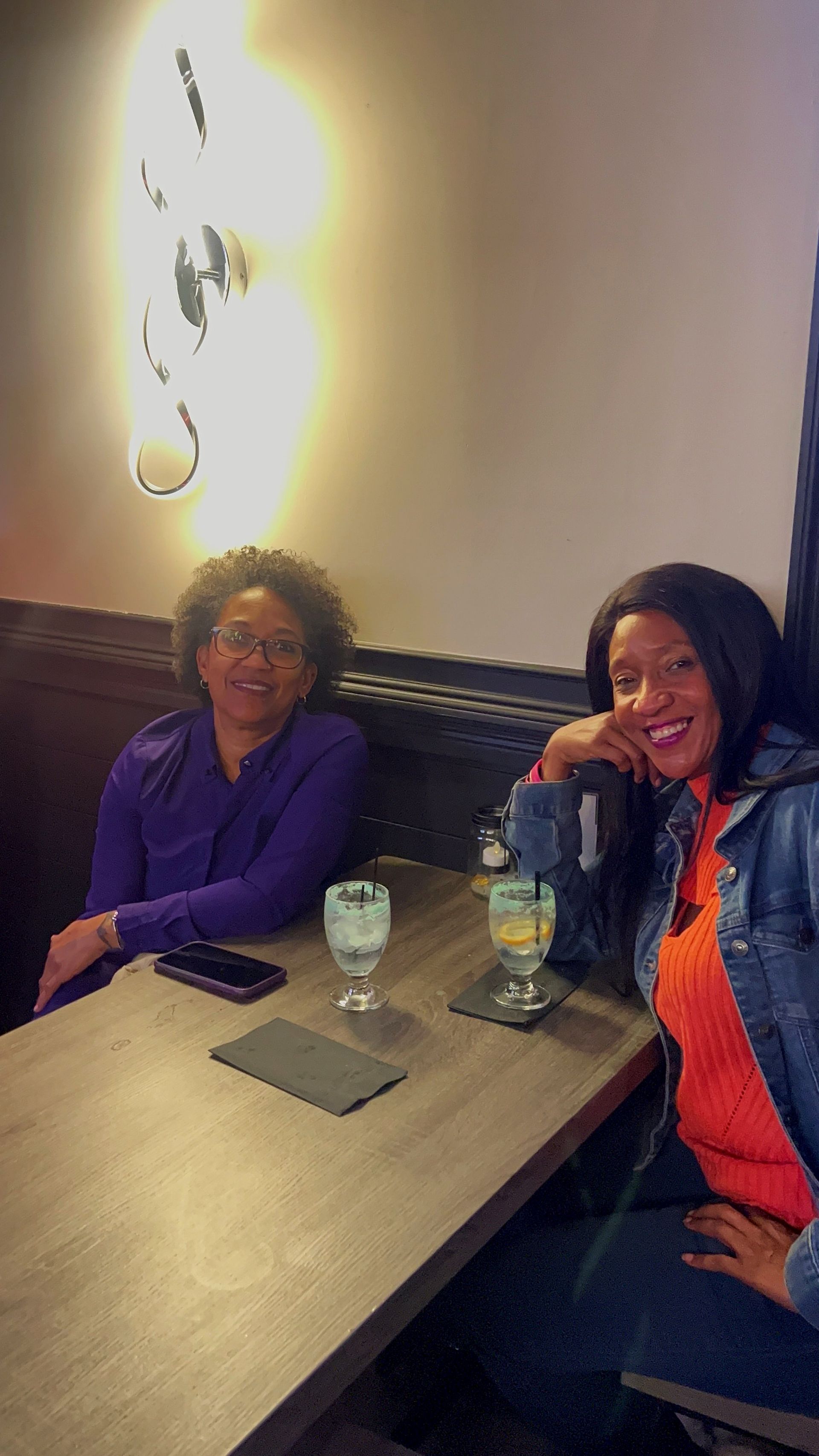 Two women are sitting at a table in a restaurant.