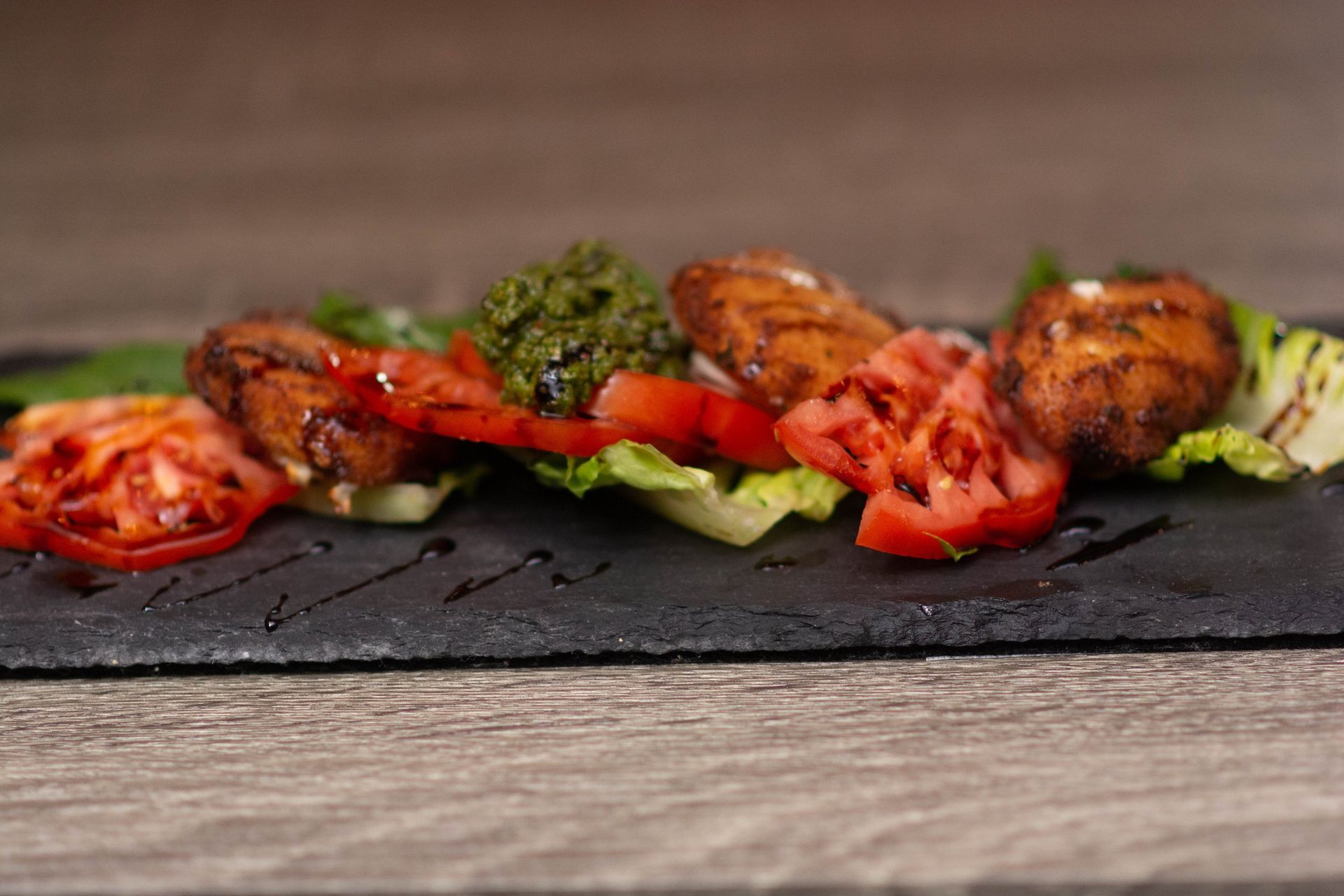 A close up of a plate of food with tomatoes and lettuce on a table.