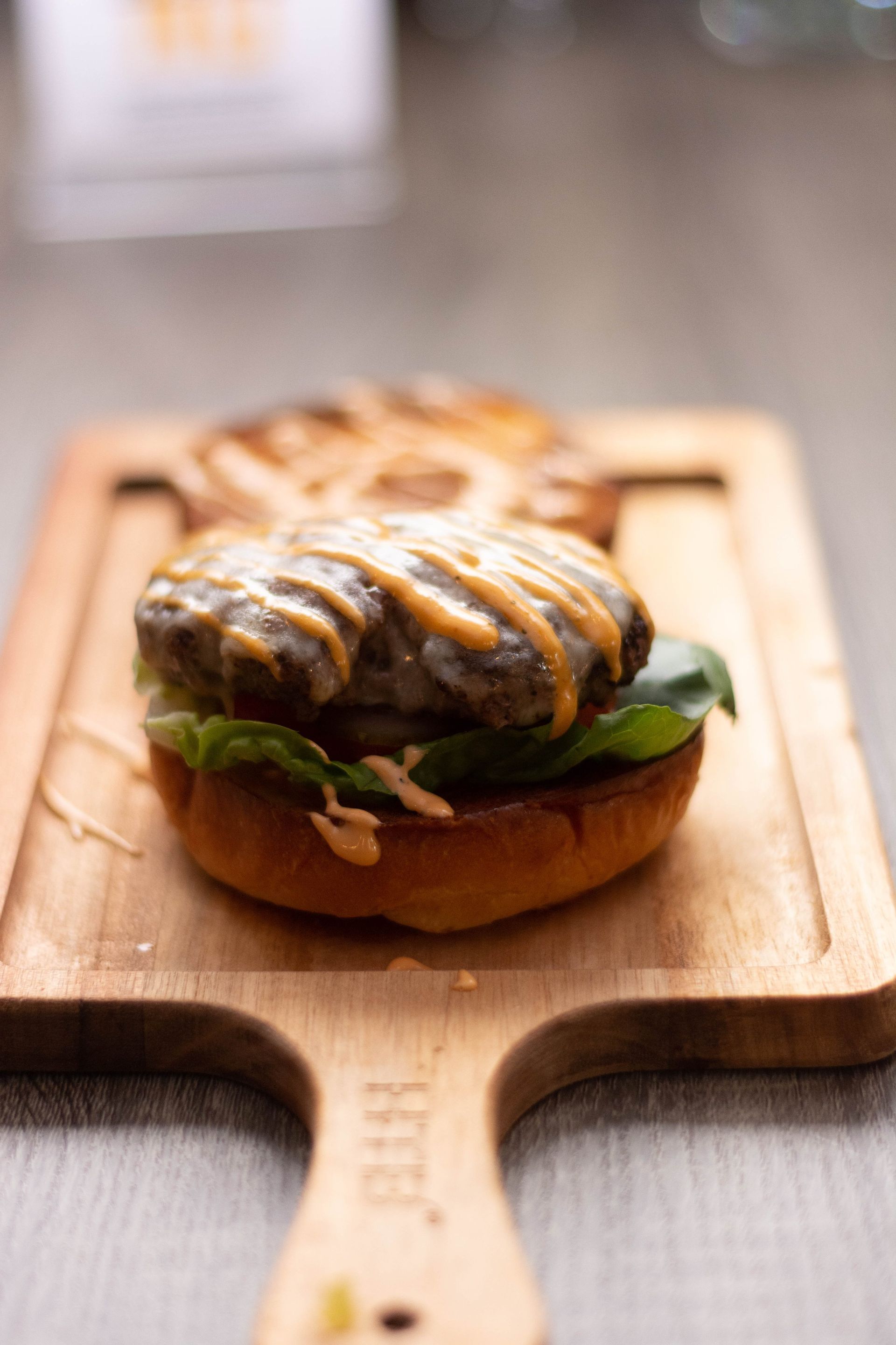 A hamburger is sitting on a wooden cutting board.