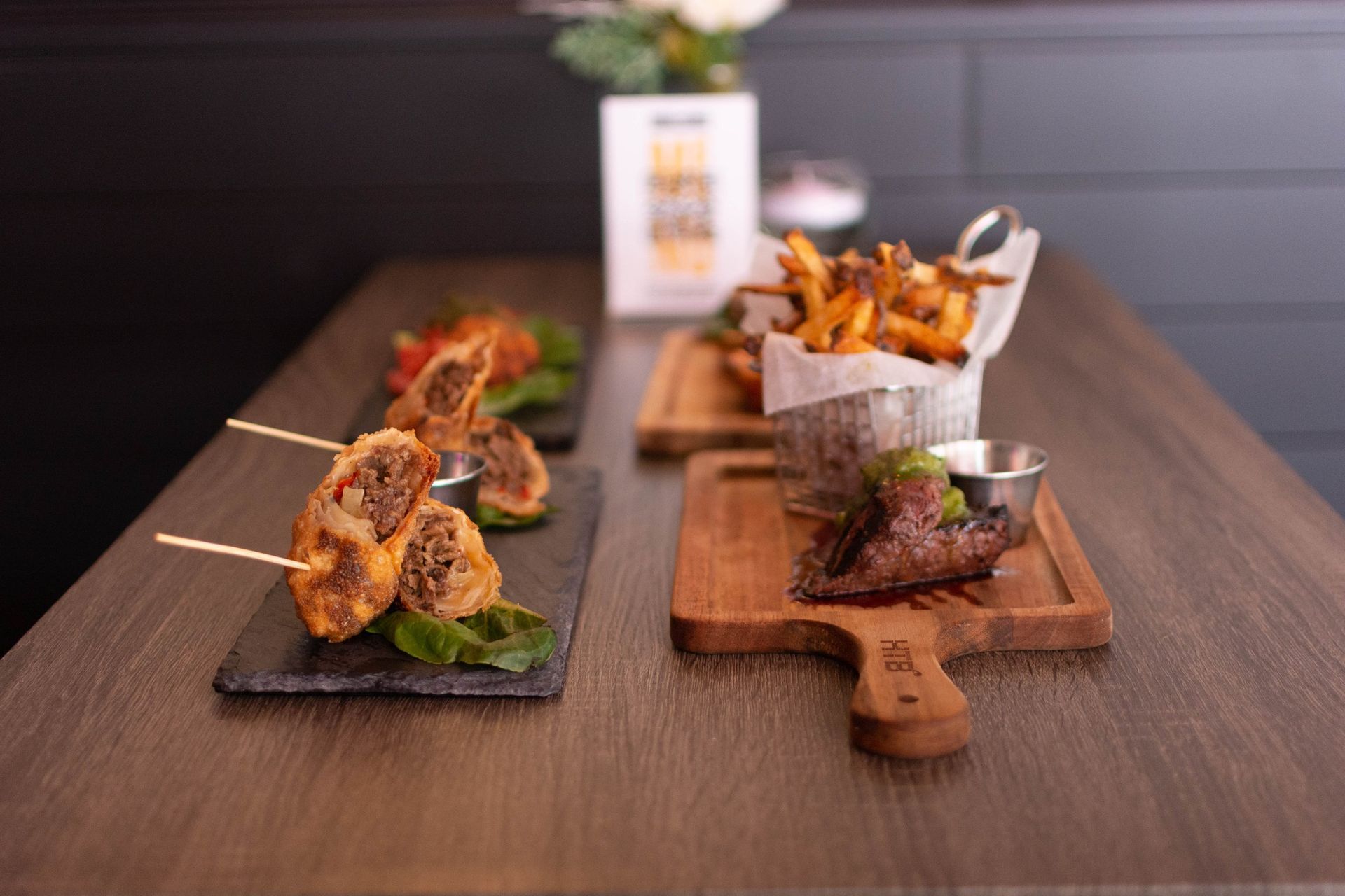 A wooden table topped with plates of food and french fries.