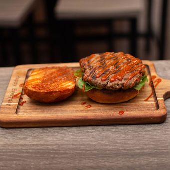 A hamburger on a bun is on a wooden cutting board