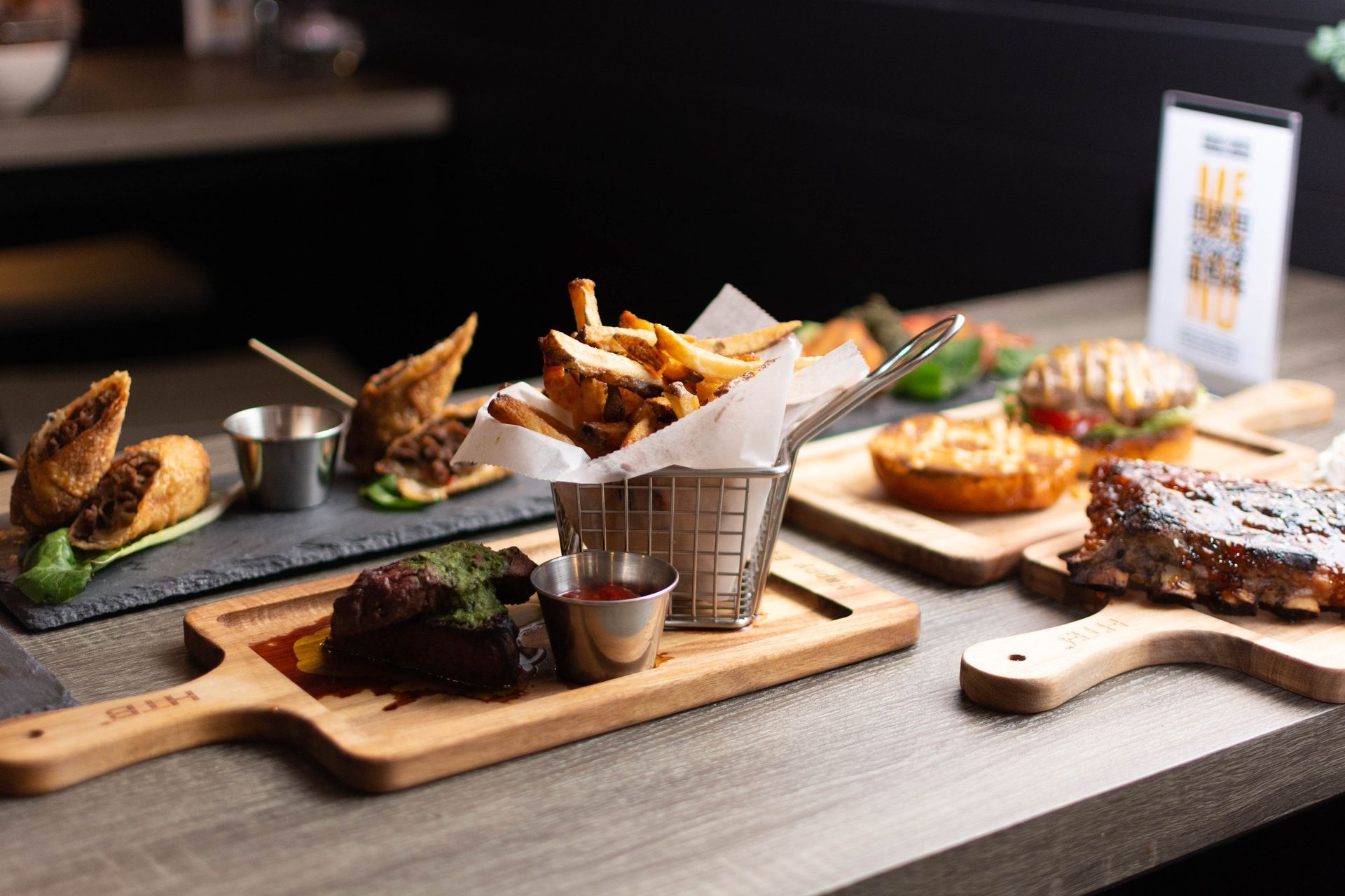 A table topped with plates of food and a basket of french fries.