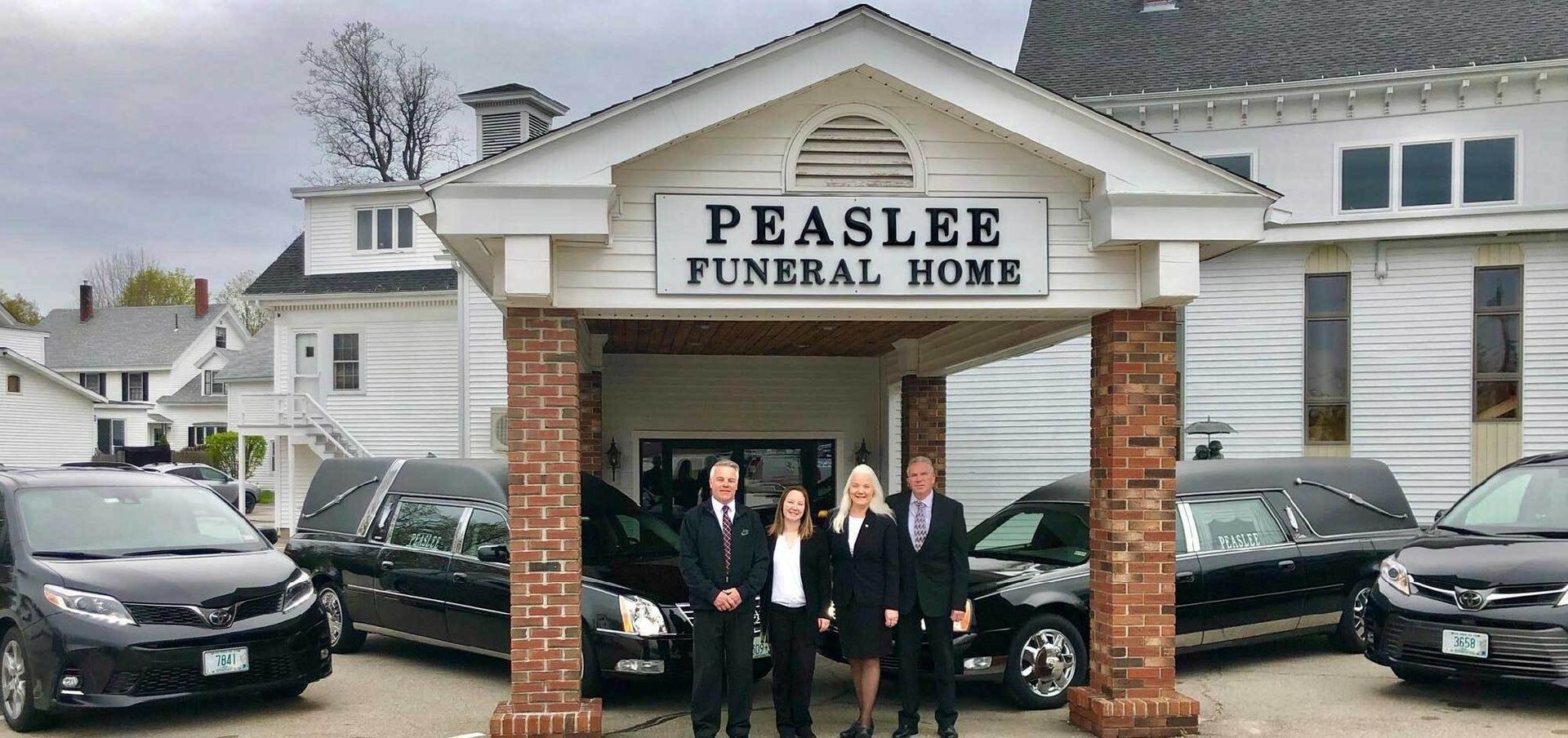 The front door of a house with a porch and plants in front of it.