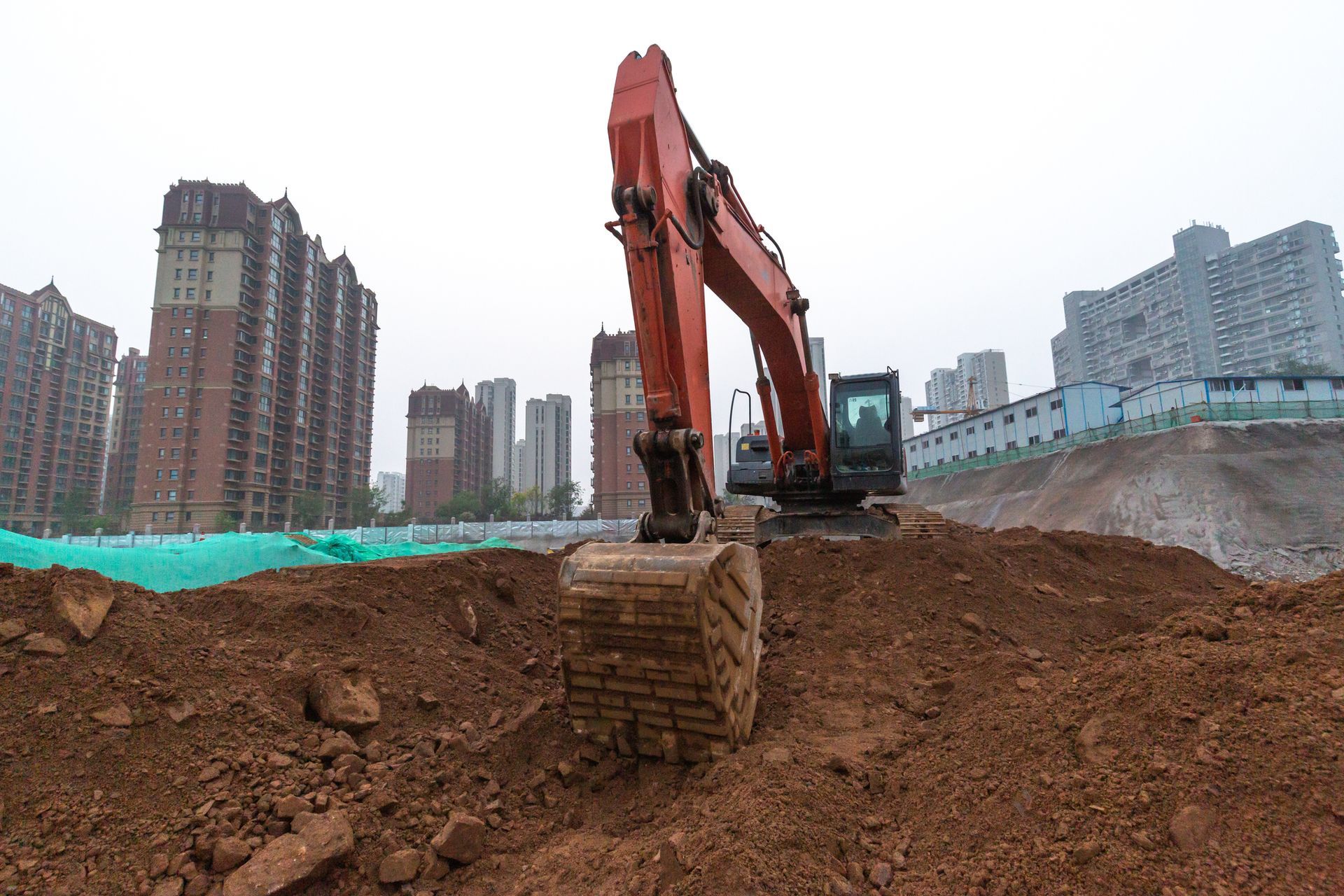 A large excavator is sitting on top of a pile of dirt on a construction site.