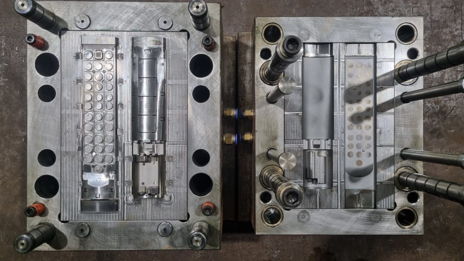 Two open metal molds used for plastic injection molding.