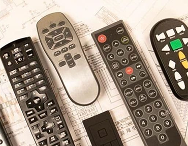 Five various black and silver remote controls on a printed sheet with writing.