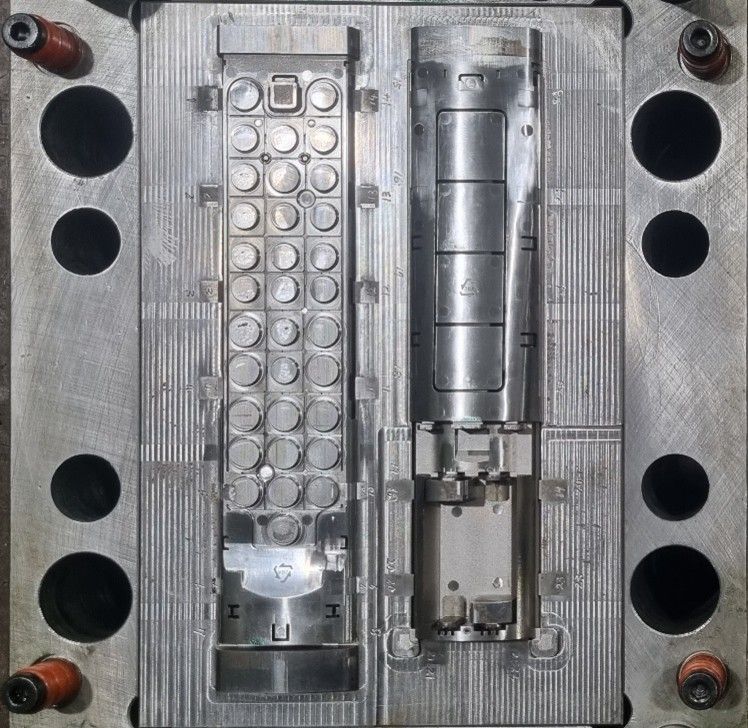 Open metal mold with cavities for two remote control halves.