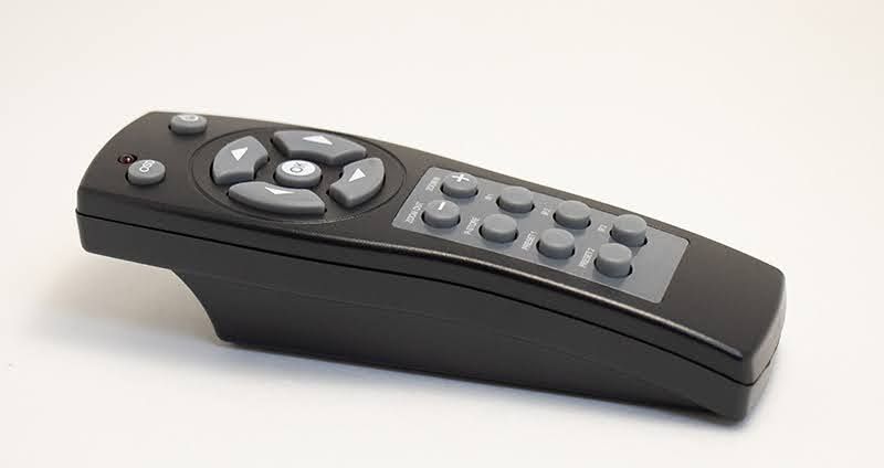 Black remote control with gray buttons on a white surface.