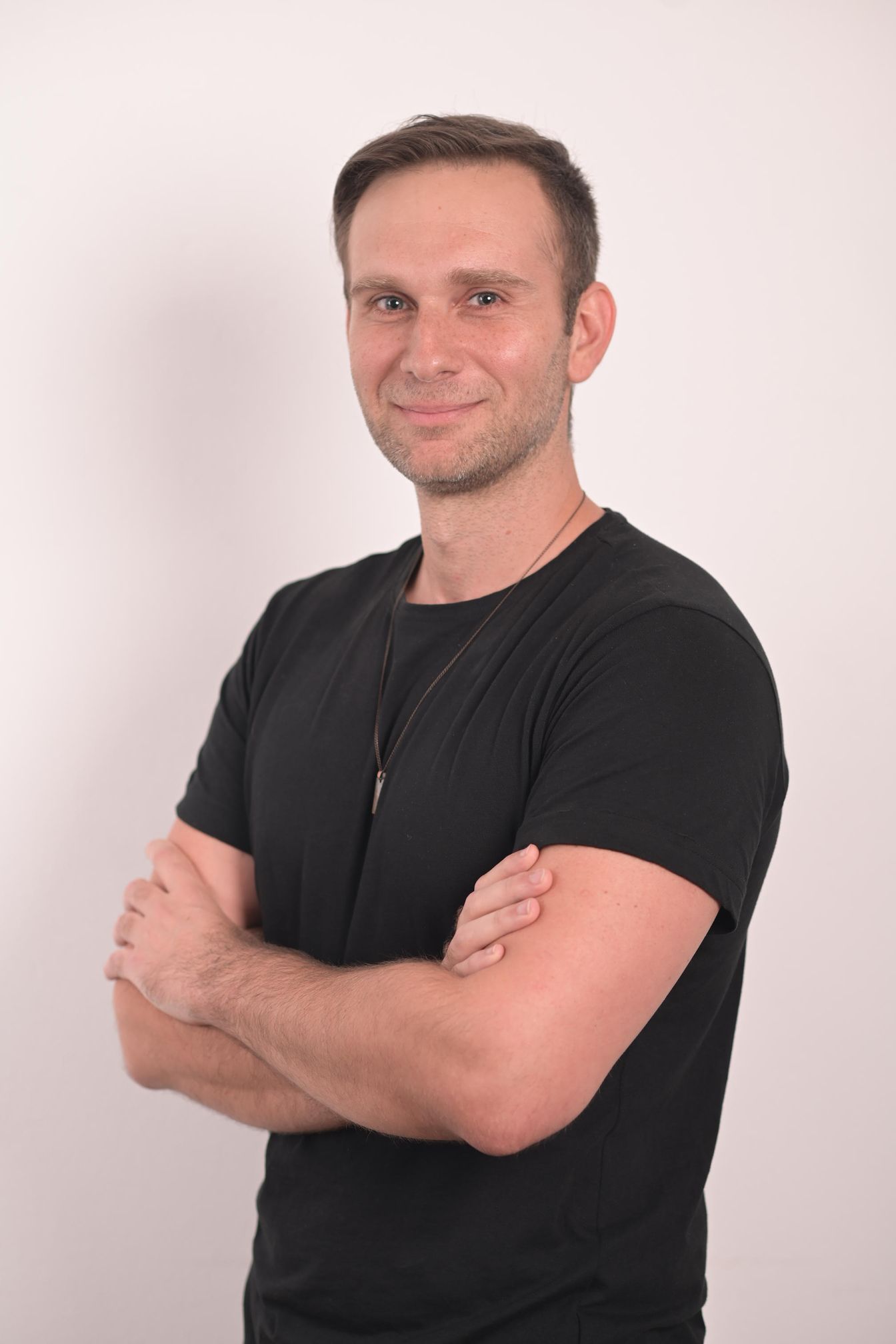 A man in a black shirt is standing with his arms crossed.