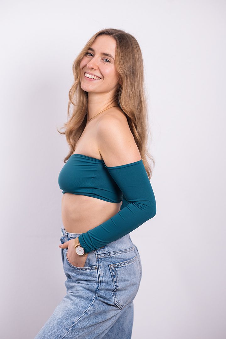 The woman is wearing a crop top and jeans and smiling.