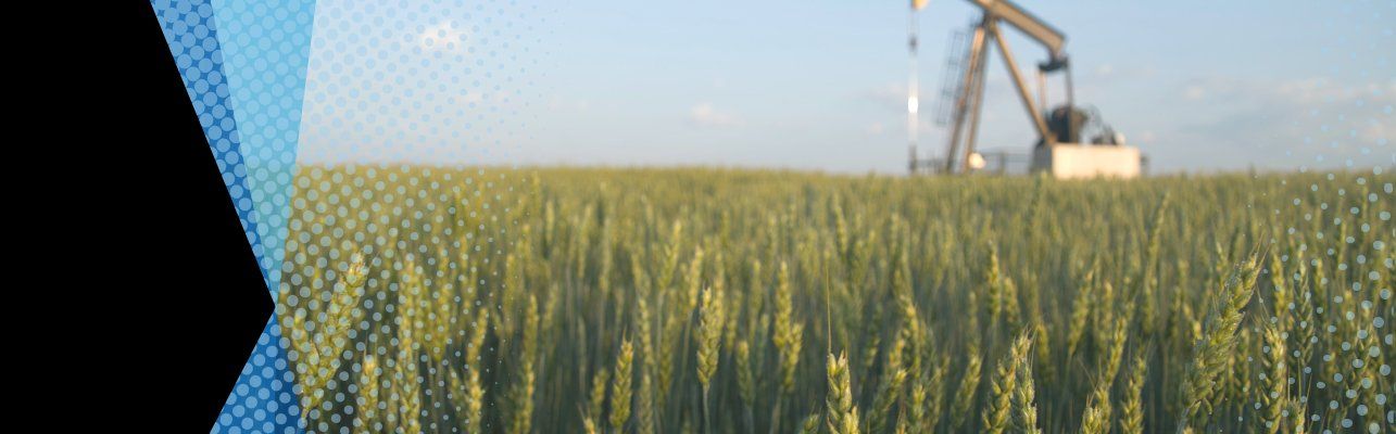 A picturesque wheat field with a large pump in the background.