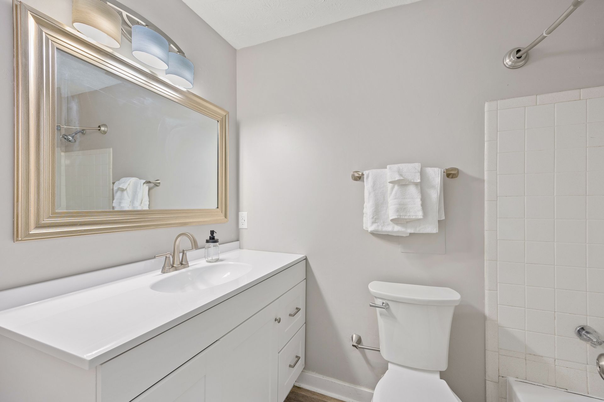 Open-concept living room with ceiling fan, large windows, and wood-style flooring.