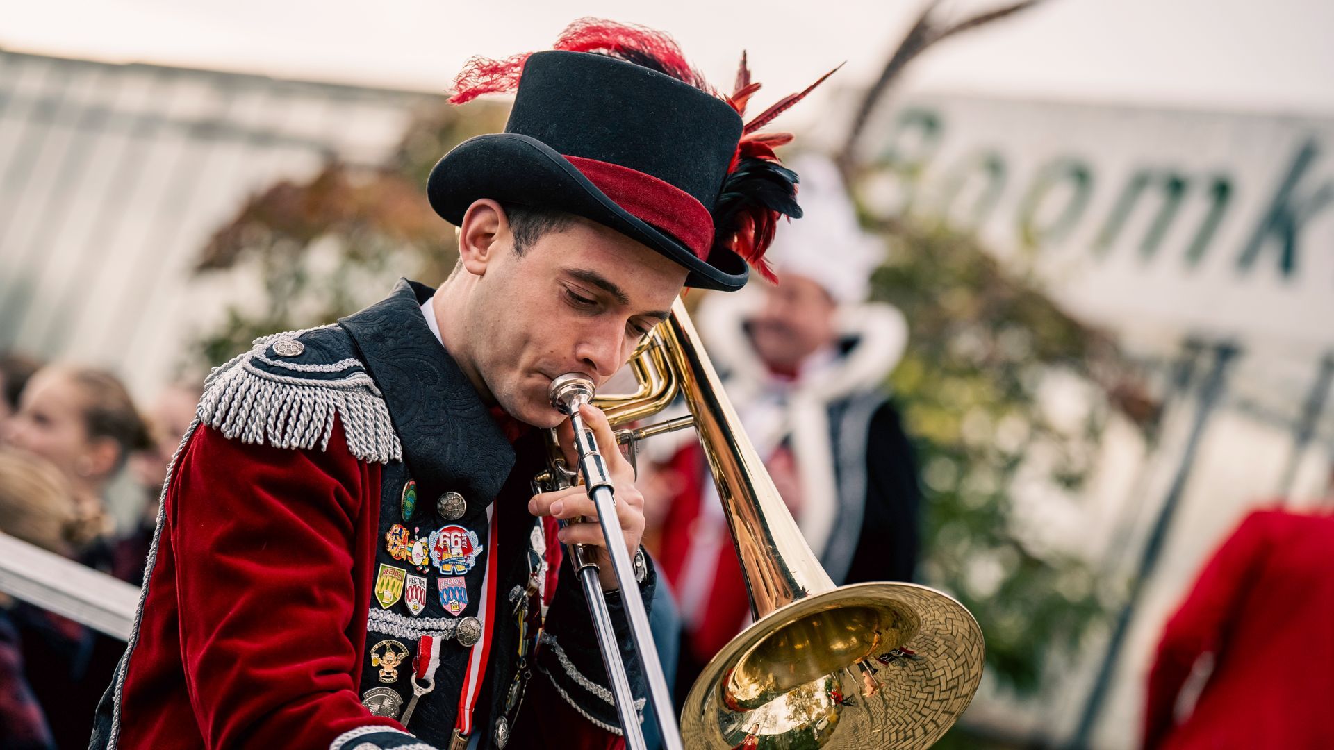 Een man met een hoge hoed bespeelt trombone in een band.