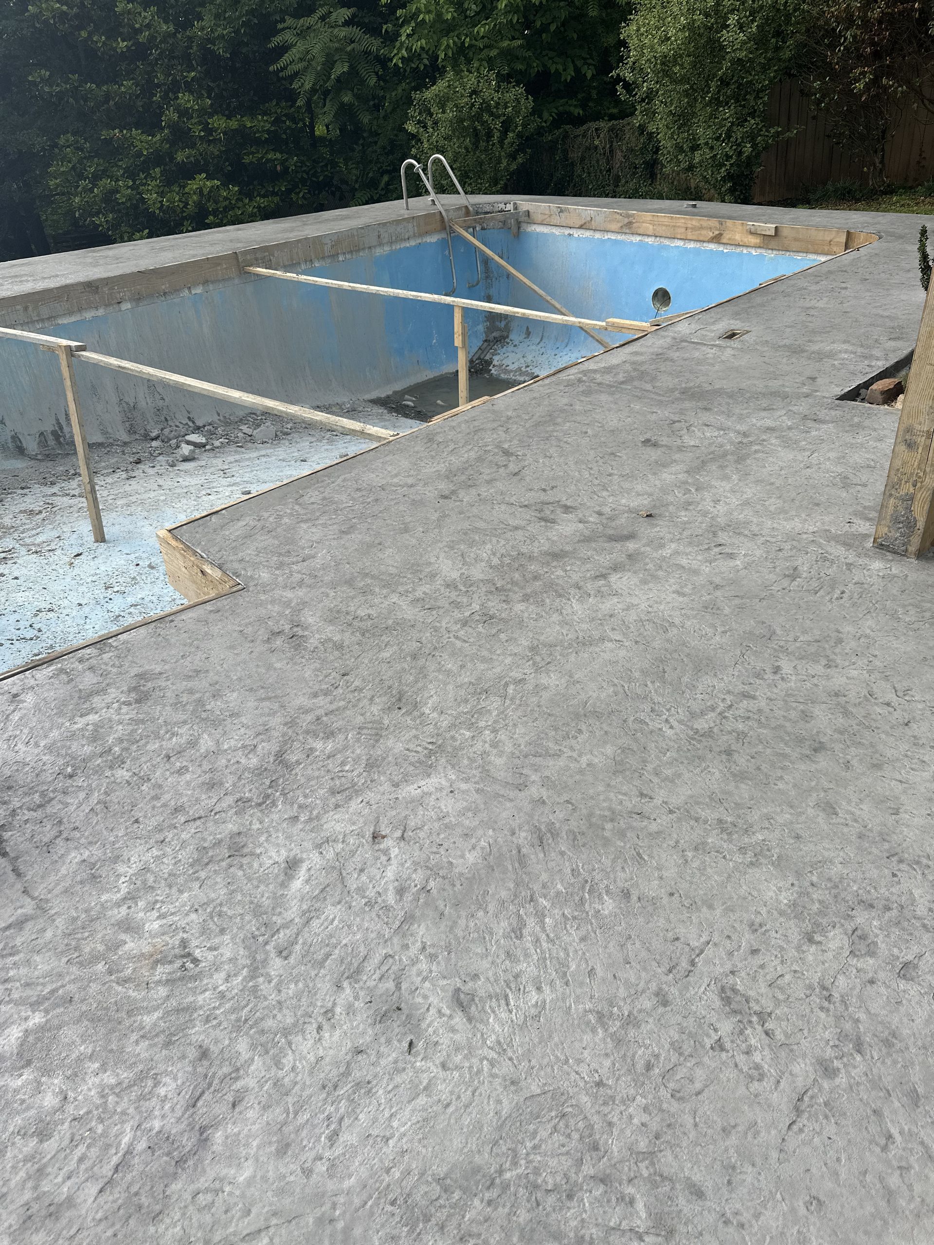 An empty swimming pool is sitting on top of a concrete roof.