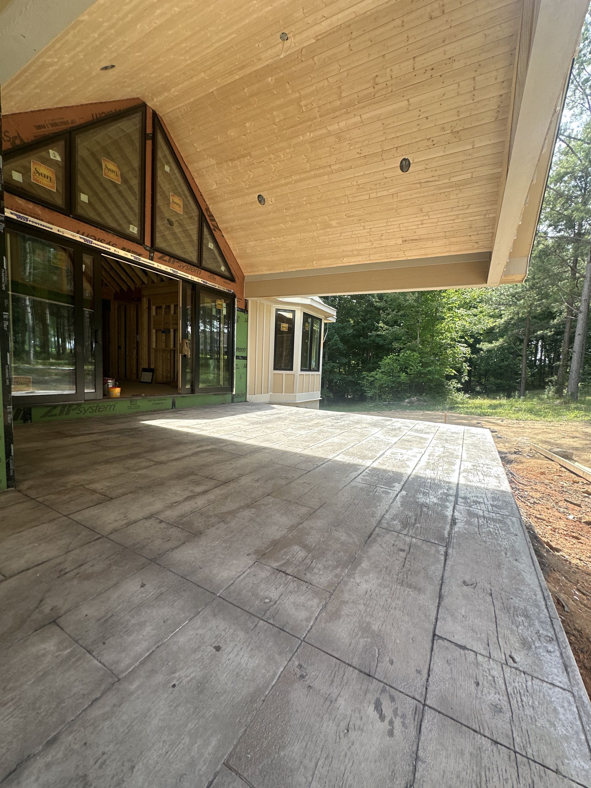 A large covered patio with a wooden ceiling and a lot of windows.