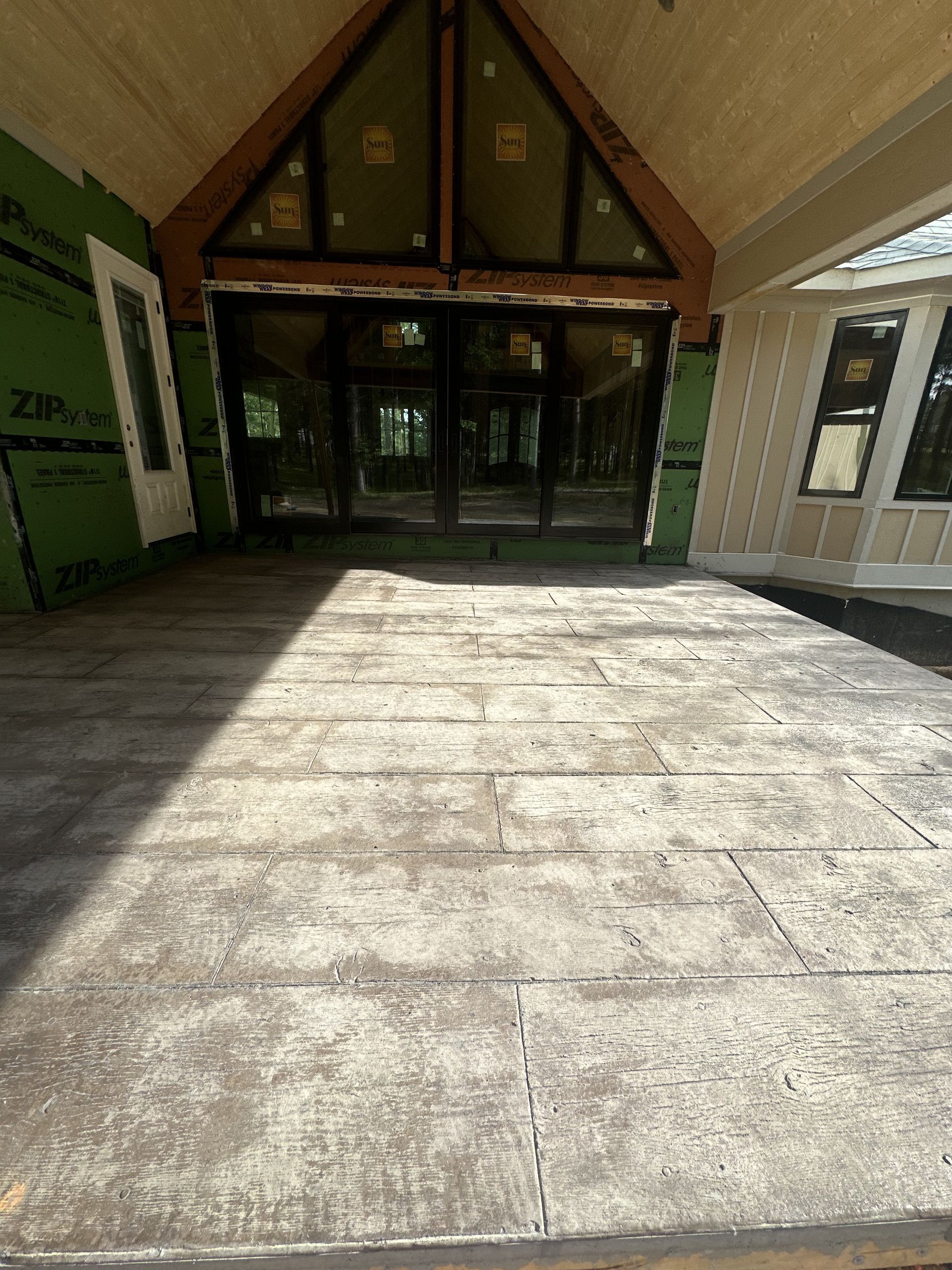 A large concrete patio in front of a house under construction.
