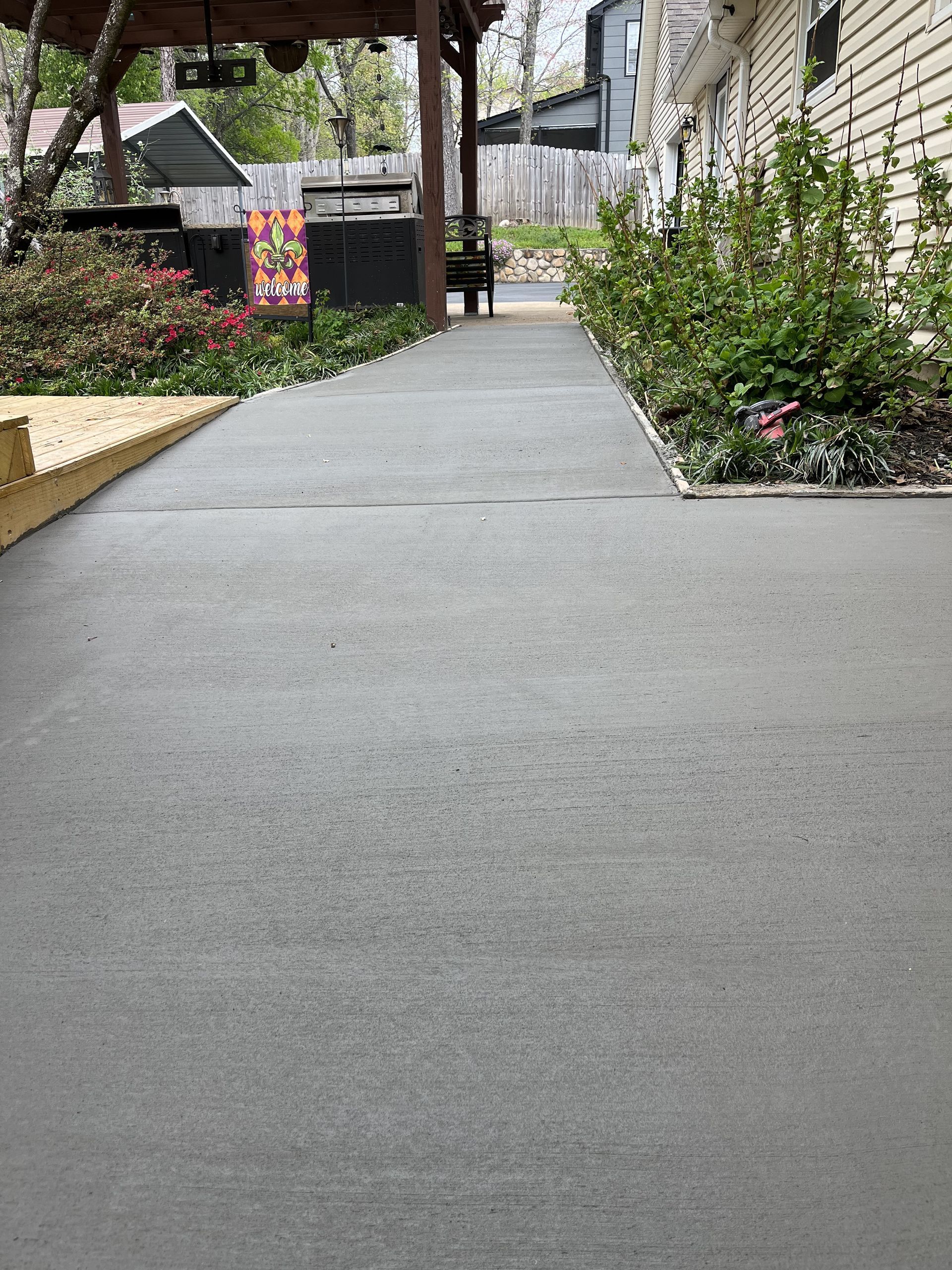 A concrete walkway leading to a house with a pergola.