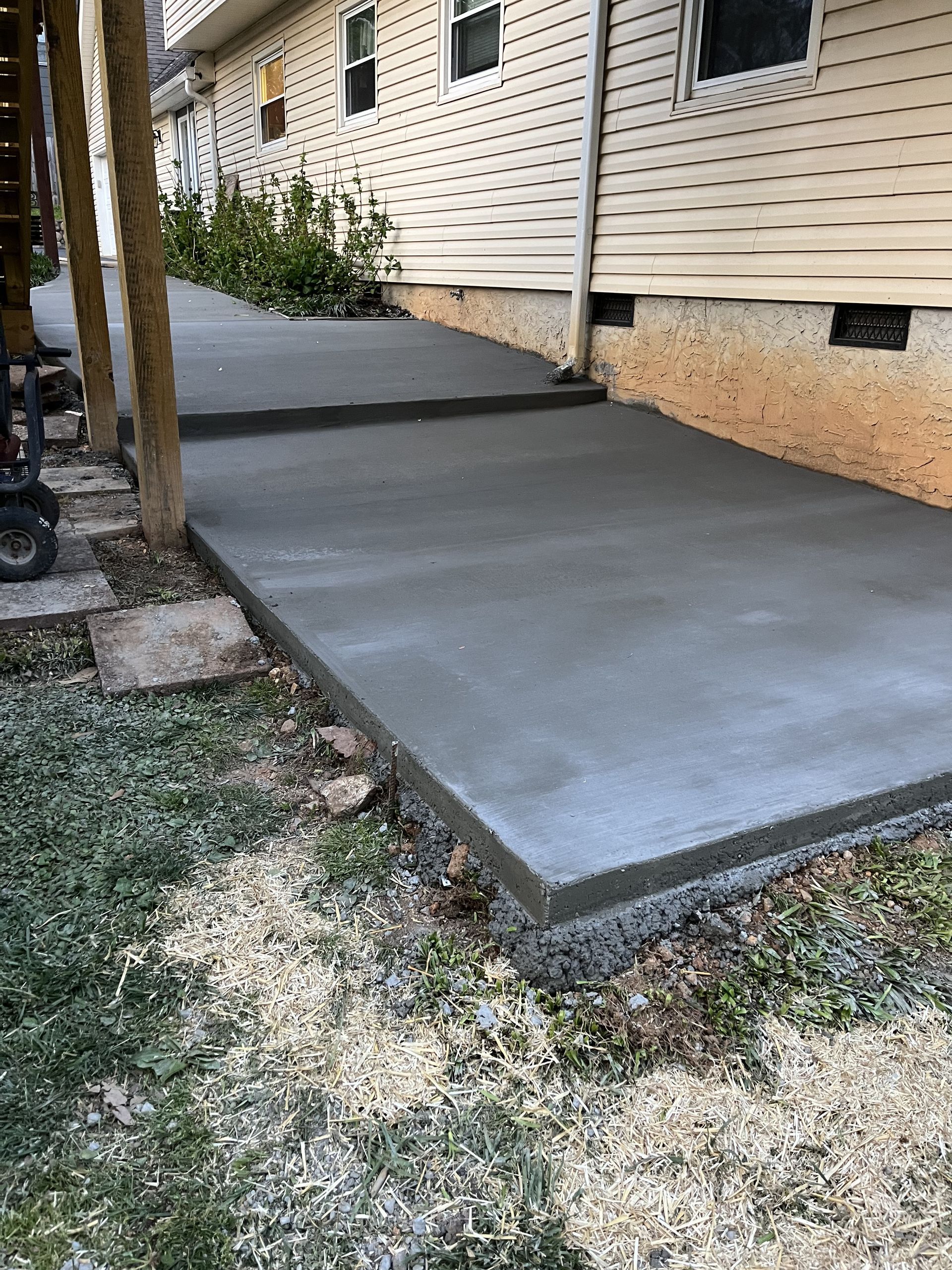 A concrete walkway is being built in front of a house.