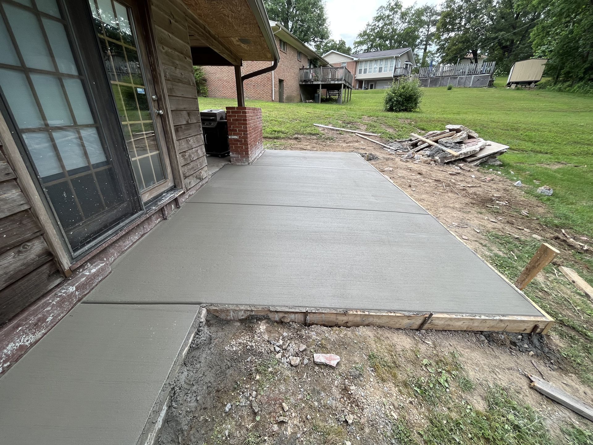 A concrete patio is being built in front of a house.