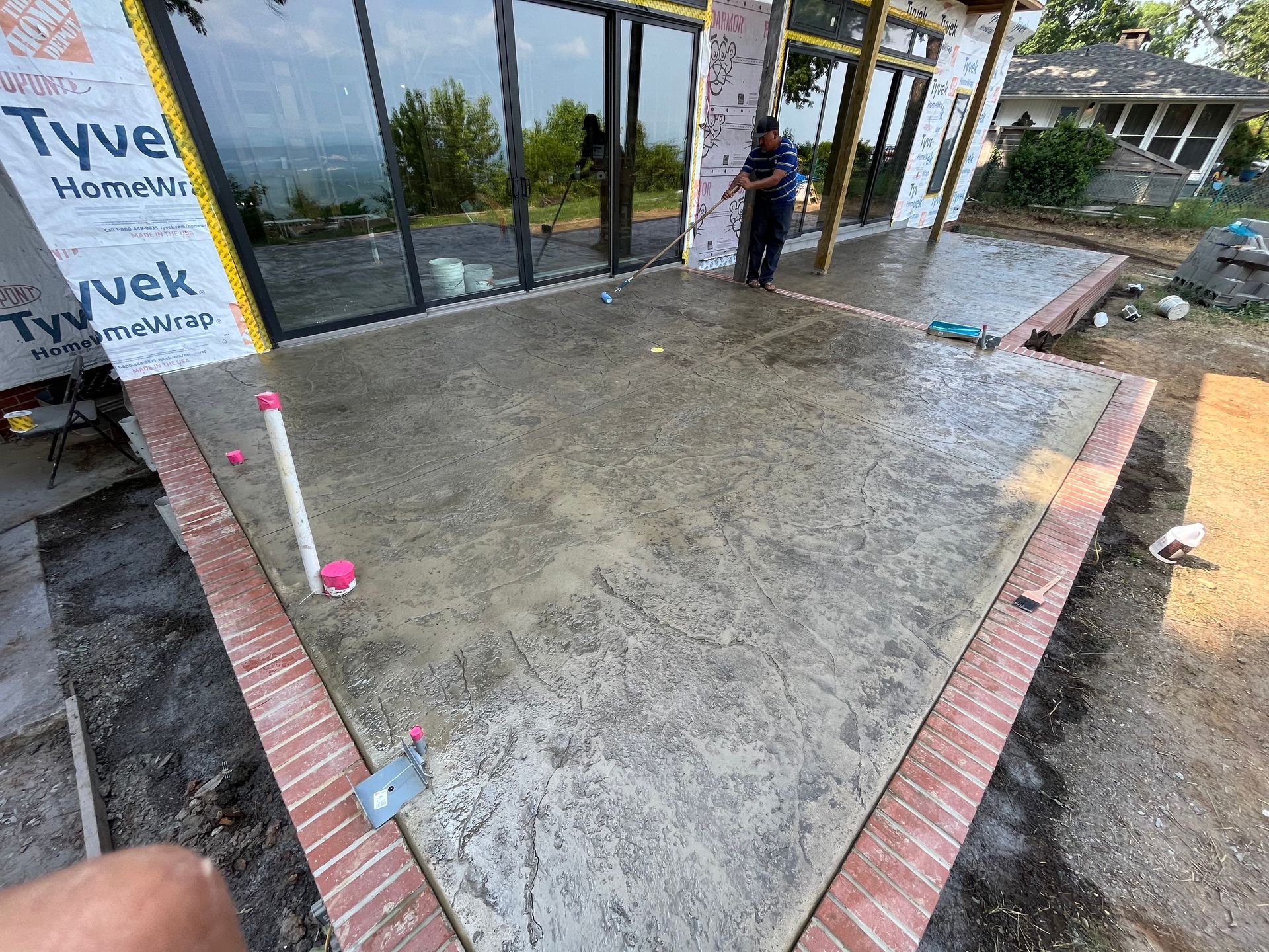 A man is standing on a concrete patio in front of a building.